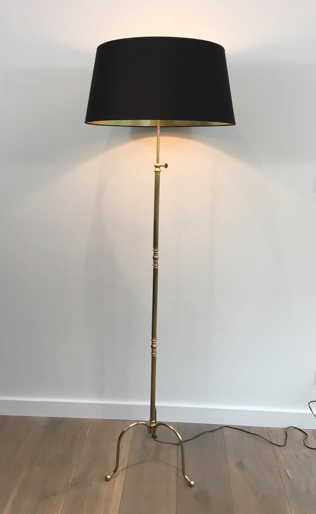This neoclassical floor lamp is made of brass. It has a tripode base, decorations on the central brass part and is adjustable so can be lower or higher as needed. This is a French work, in the style of famous French Maison Jansen, circa 1940.