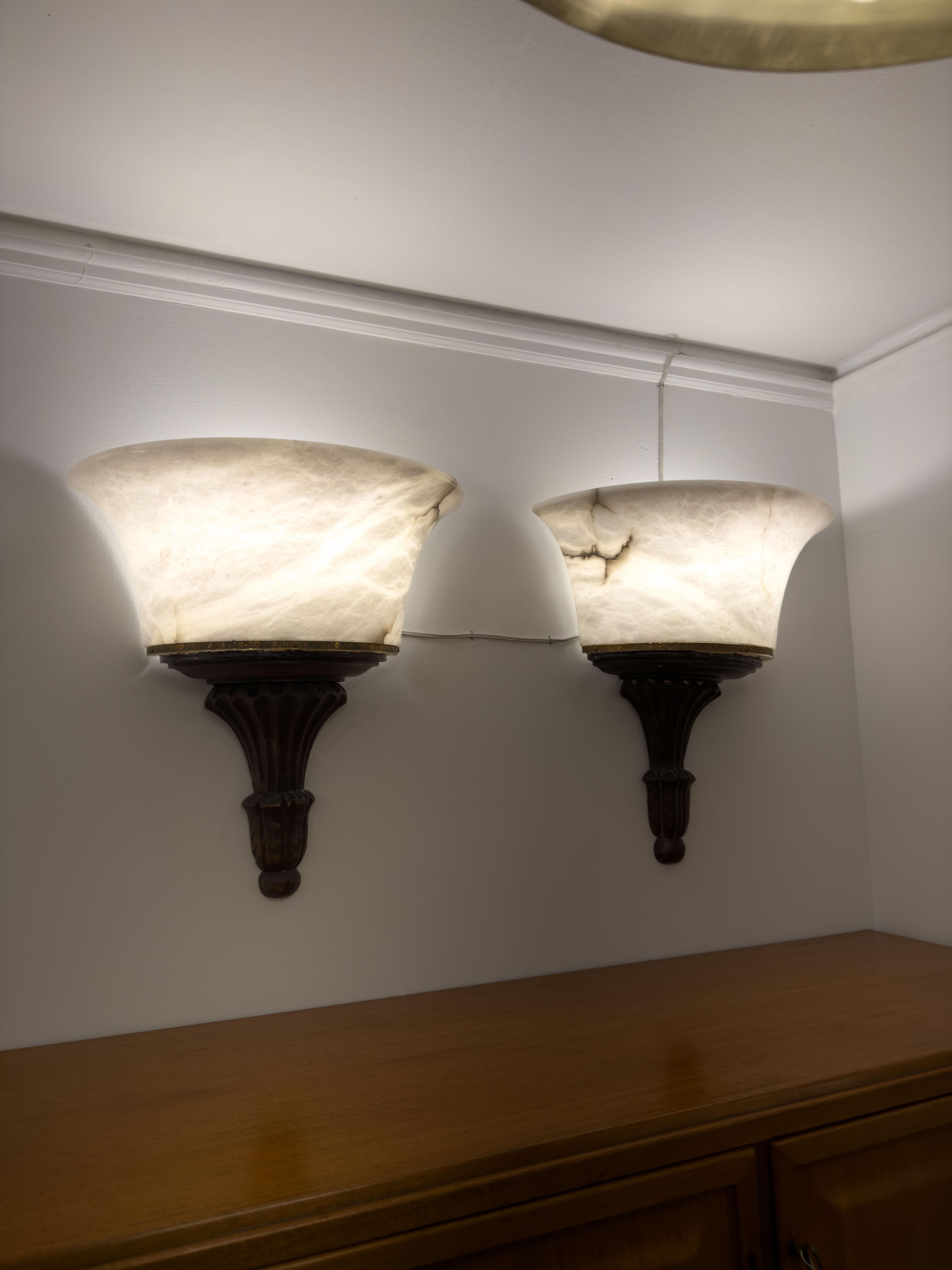 Illuminate your space with sophistication and elegance with our Neoclassical Alabaster Torches. Each torch boasts a white alabaster shade, featuring stunning mineralization and light veining, and is illuminated by a dimmable LED bulb. Mounted on a