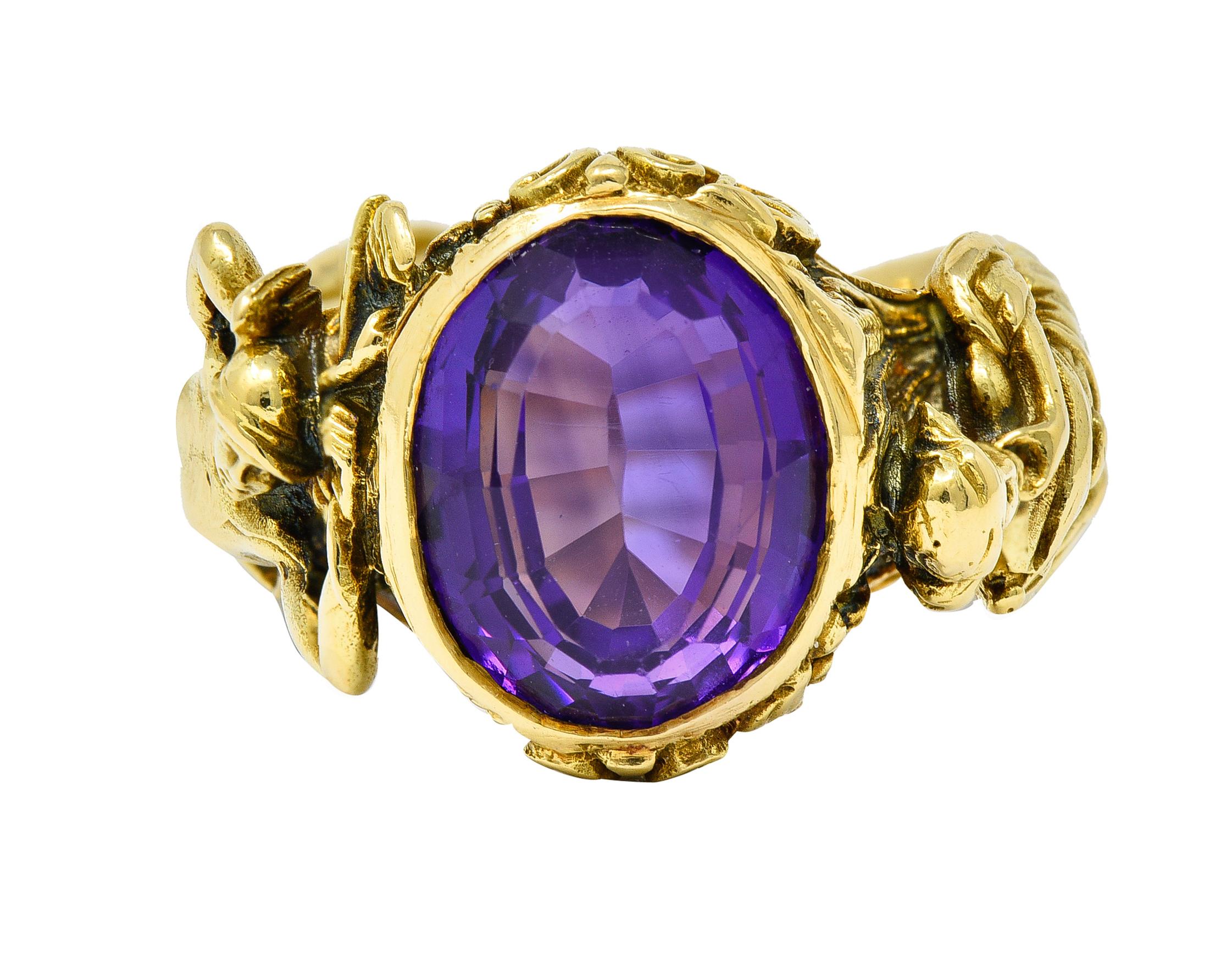 Centering on oval mixed step cut amethyst measuring approximately 12.5 x 10.0 mm
Transparent with medium-light and strongly purple color

Bezel set in a highly rendered mounting depicting the Hellenistic figures of Hermes and Demeter

Male figure is