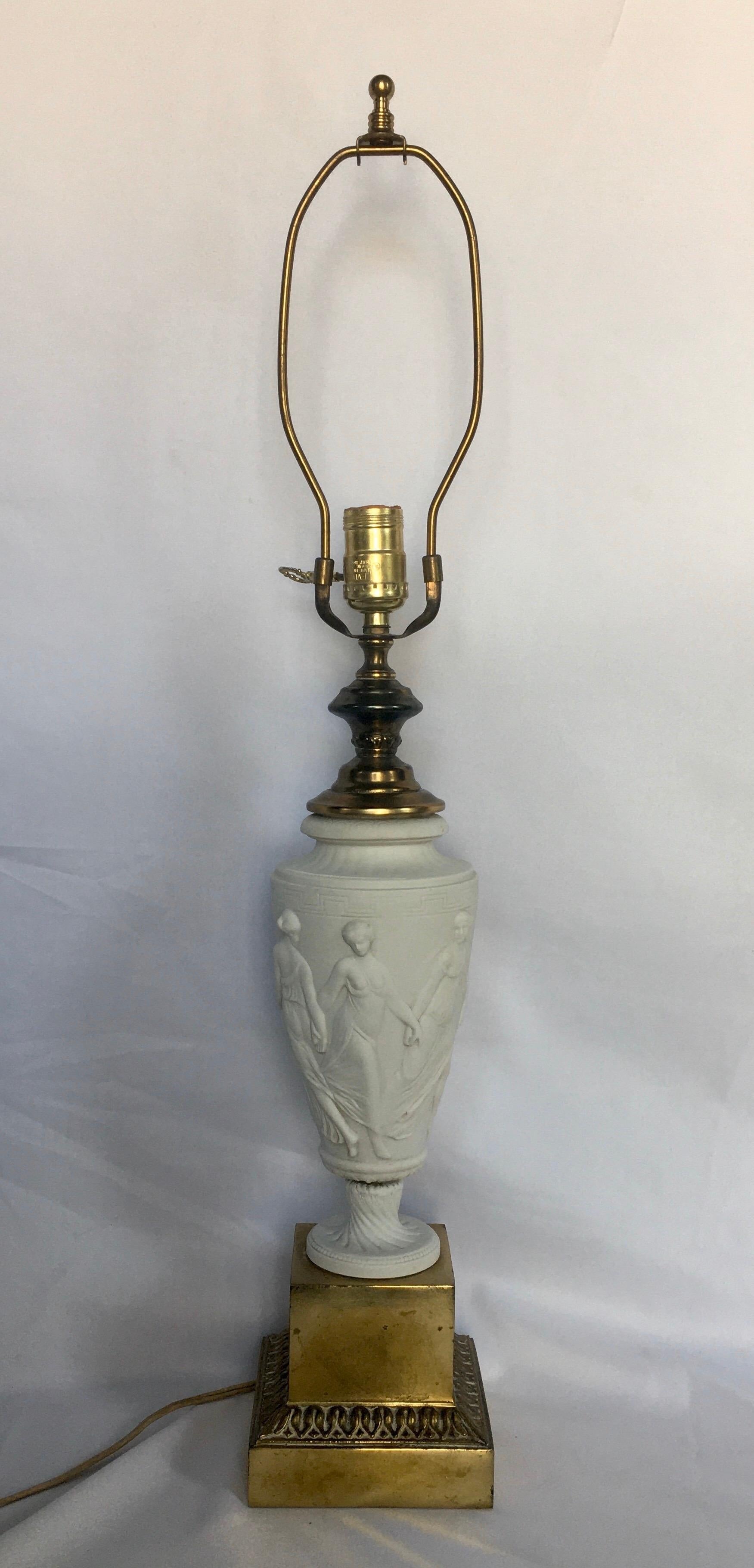 Neoclassical style matte white bisque porcelain table lamp made in Bulgaria, Germany. This Classic urn shaped lamp is mounted on a brass plinth base and features dimensional figures and Greek key motifs. Marked 