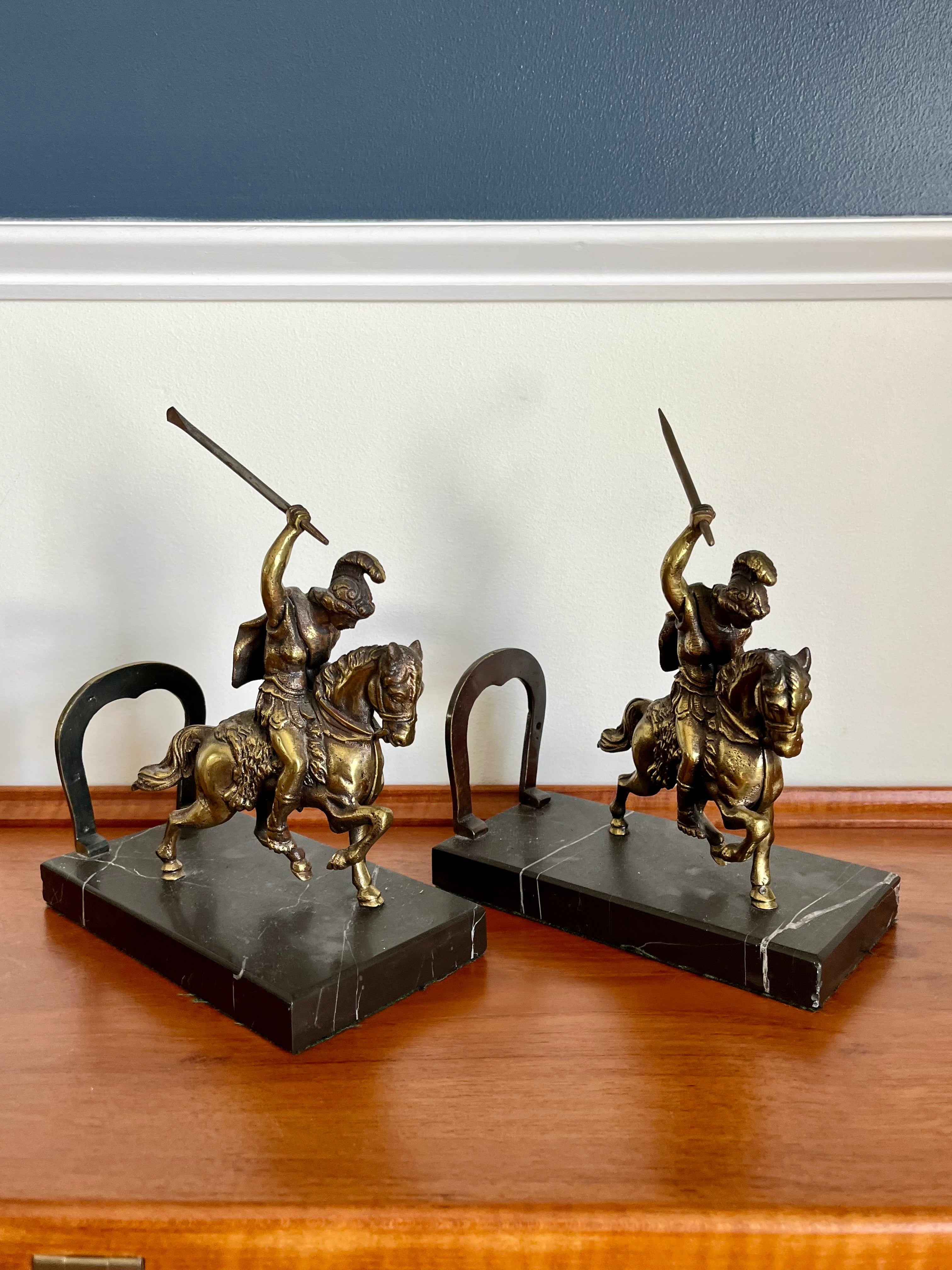 Splendida coppia di fermalibri neoclassici. Soldati romani con spade alzate in cima a cavalli in corsa. Figure in metallo dorato montate su una base di marmo nero. Fermate a ferro di cavallo.
