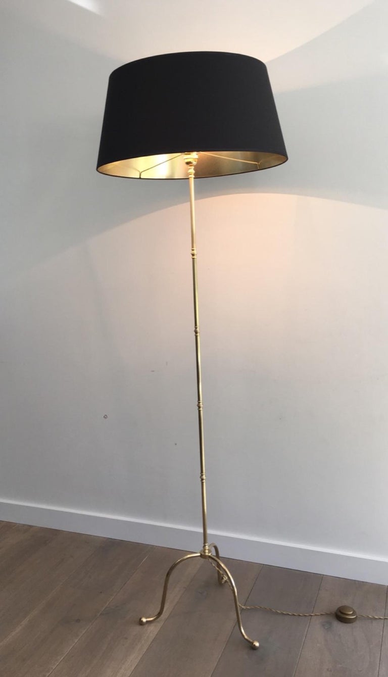 This neoclassical tripod floor lamp is made of brass with a black shintz shade gild inside. This floor lamp from 1940s is attributed to the famous Maison Jansen designer.