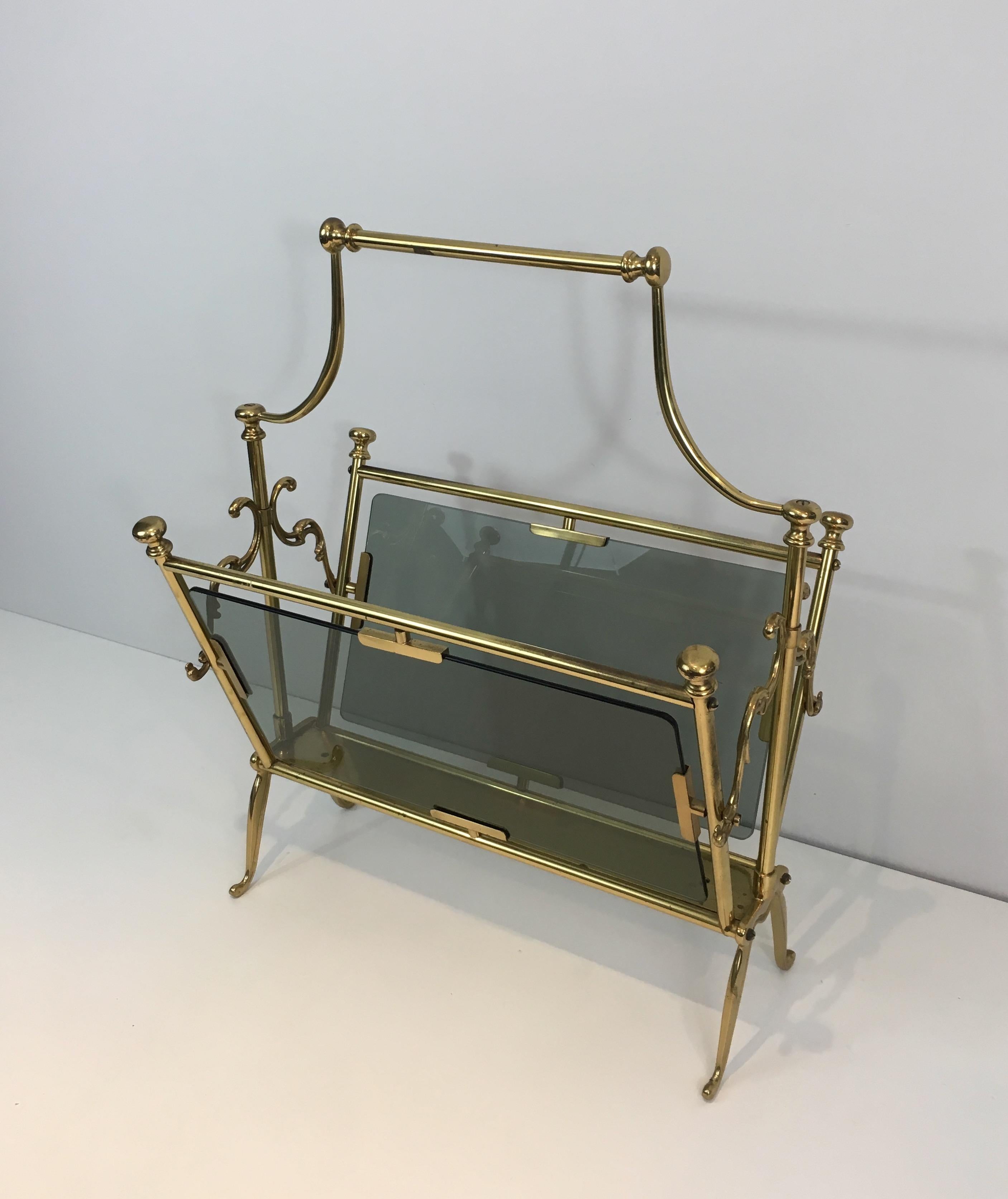This neoclassical magazine rack is made of brass with blueish glass panels on the sides. This is a French work, circa 1960.