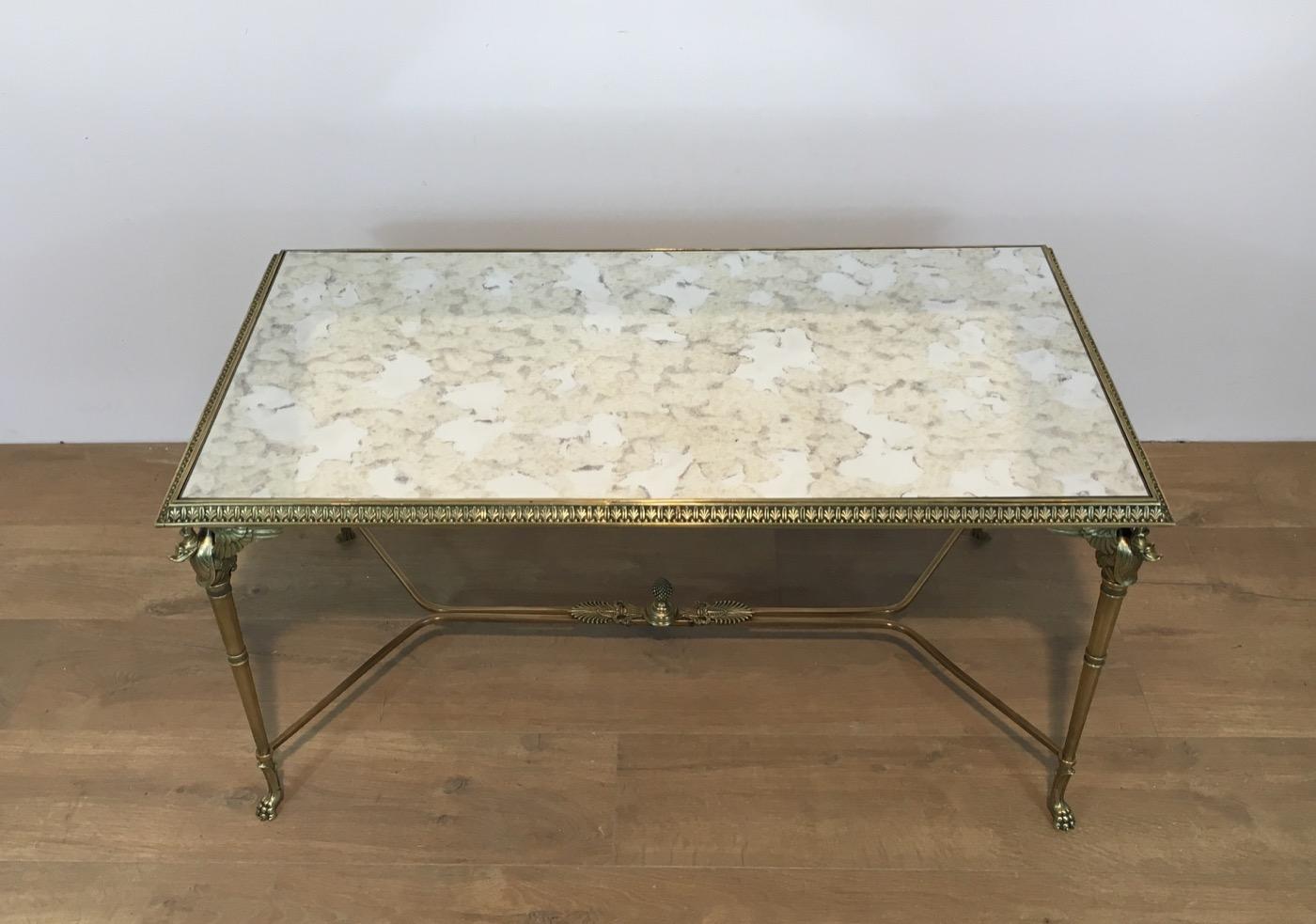This rare coffee table is made of bronze and brass with a faux-antiques mirror top. It has swan figures on each corner and claw feet. This is a very interesting coffee table, in the style of Maison Jansen. This is French, circa 1940.