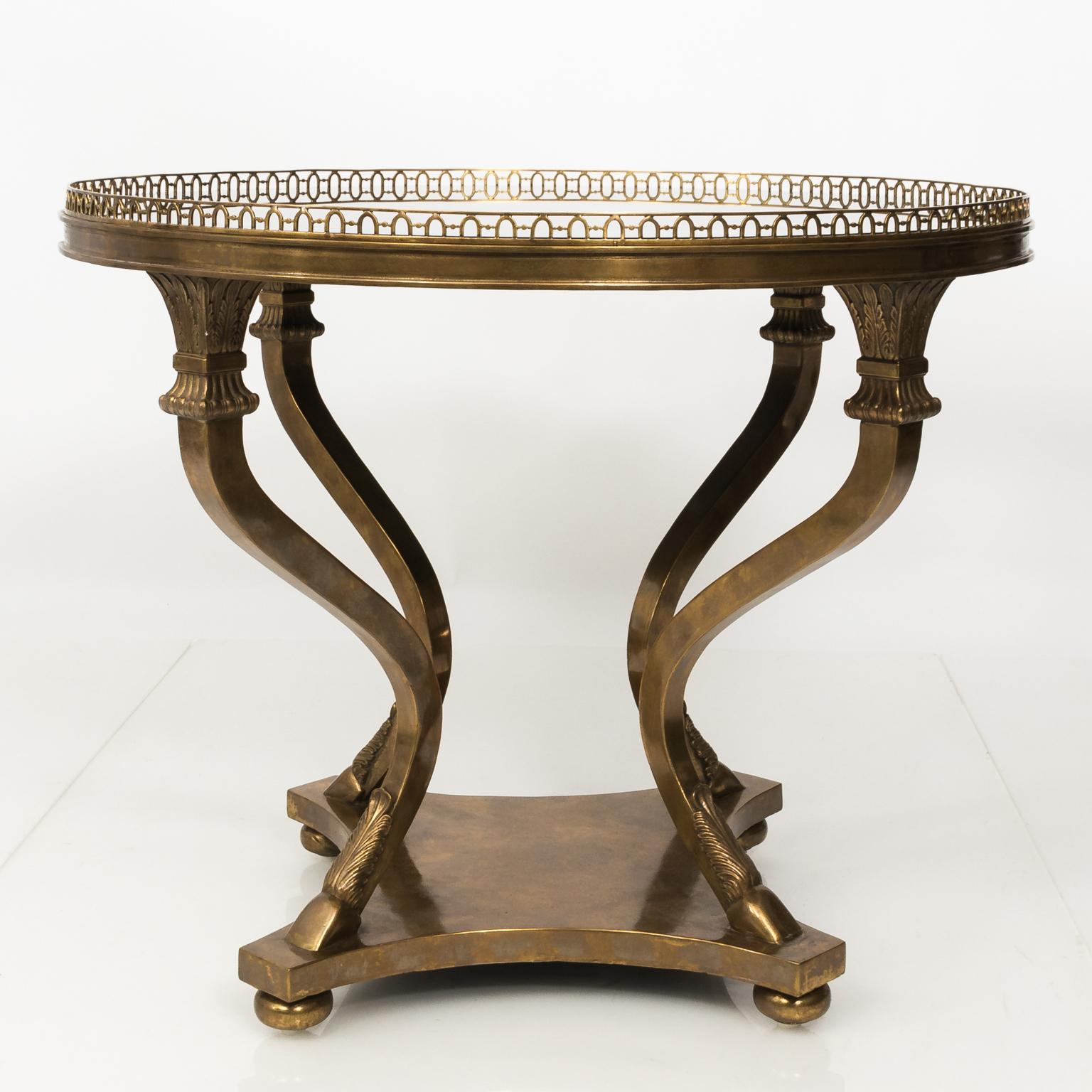 Neoclassical style bronze centre table in shape of a large guerdon with antiqued mirror top and bronze pierced gallery. Base consists of a cabriole four legged support finished with hoof and waterleaf leaf shaped feet.
  