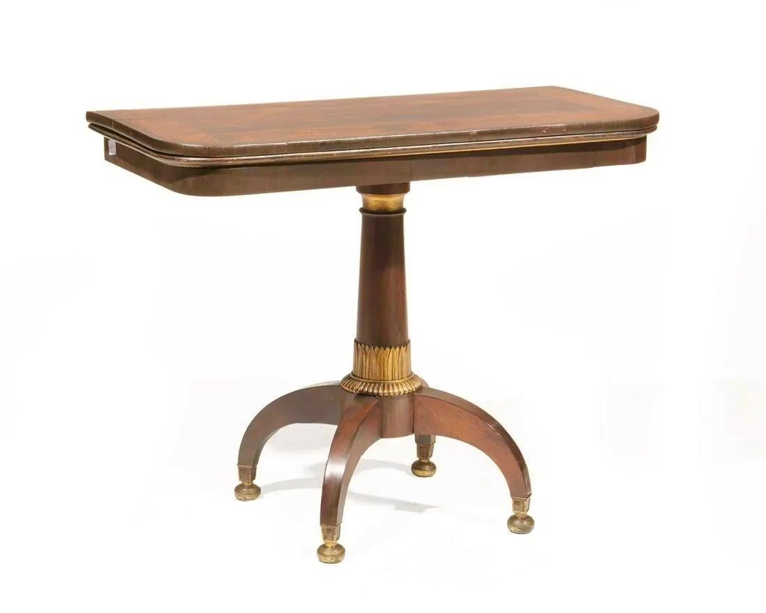 Neoclassical Rosewood and Marquetry games table. Rare and unusual form. Probably Baltic, 19th century. Fold over top, playing surface lined in baize, reverse-tapered foliate standard, arched quadripartite base, mounted with bronze bun feet.