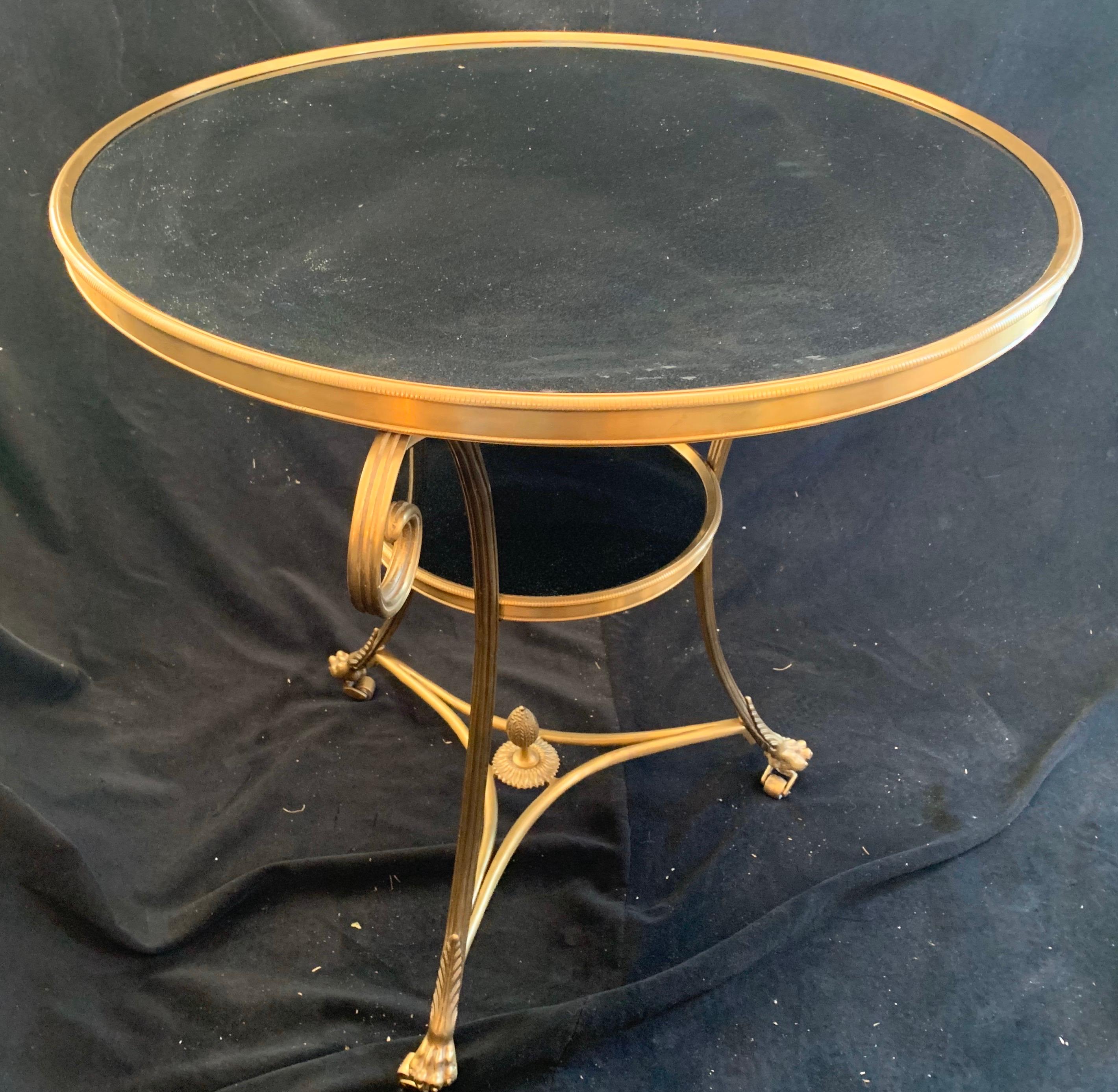 A wonderful pair of neoclassical gilt bronze ormolu and black marble top two-tier Louis XVI style gueridon tables on paw feet with casters.
