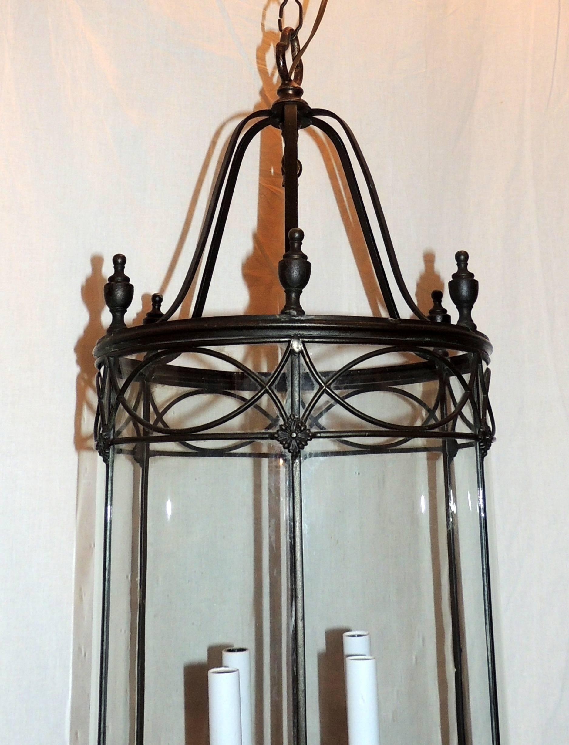 A wonderful neoclassical or regency patina bronze, panel round bent glass lantern with four candelabra lights in the manner of E.F. Caldwell finished off with urn finials all the top and a bronze tassel on the bottom. Completely rewired and ready to