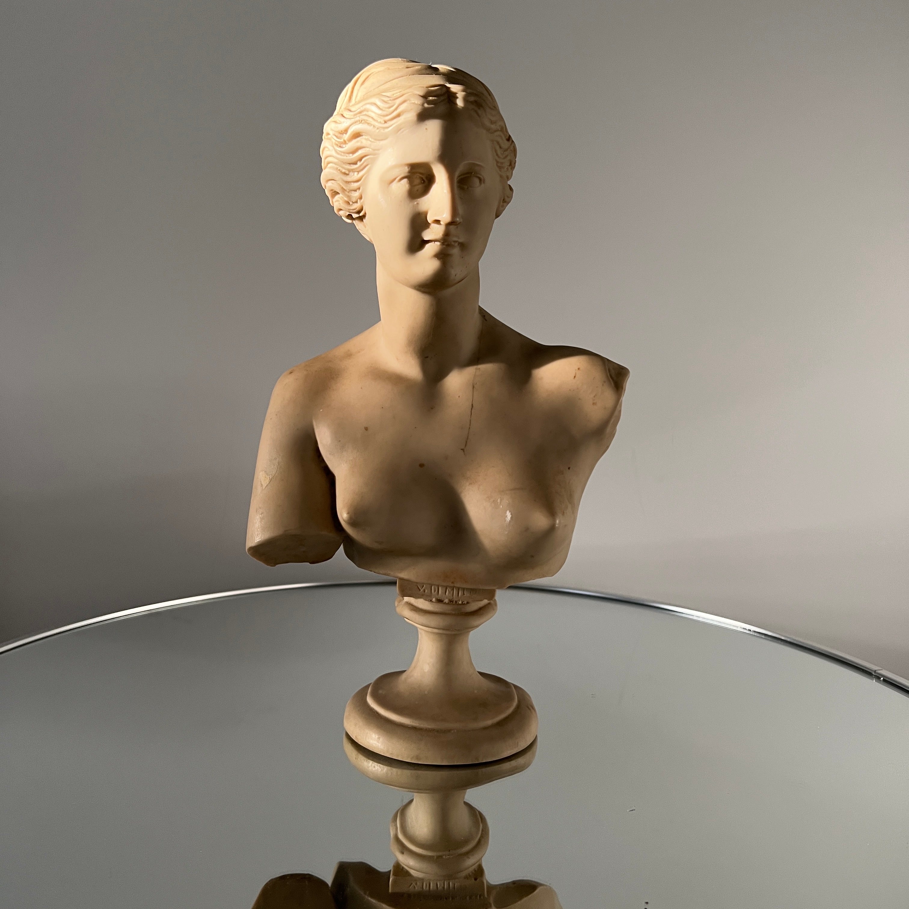 Mid-20th Century bust of Venus de Milo or Aphrodite, the goddess of love.  The sculpture sits on a pedestal base and features exquisite hand-carved details.  This replica is based on the ancient Greek sculpture created during the Hellenistic period