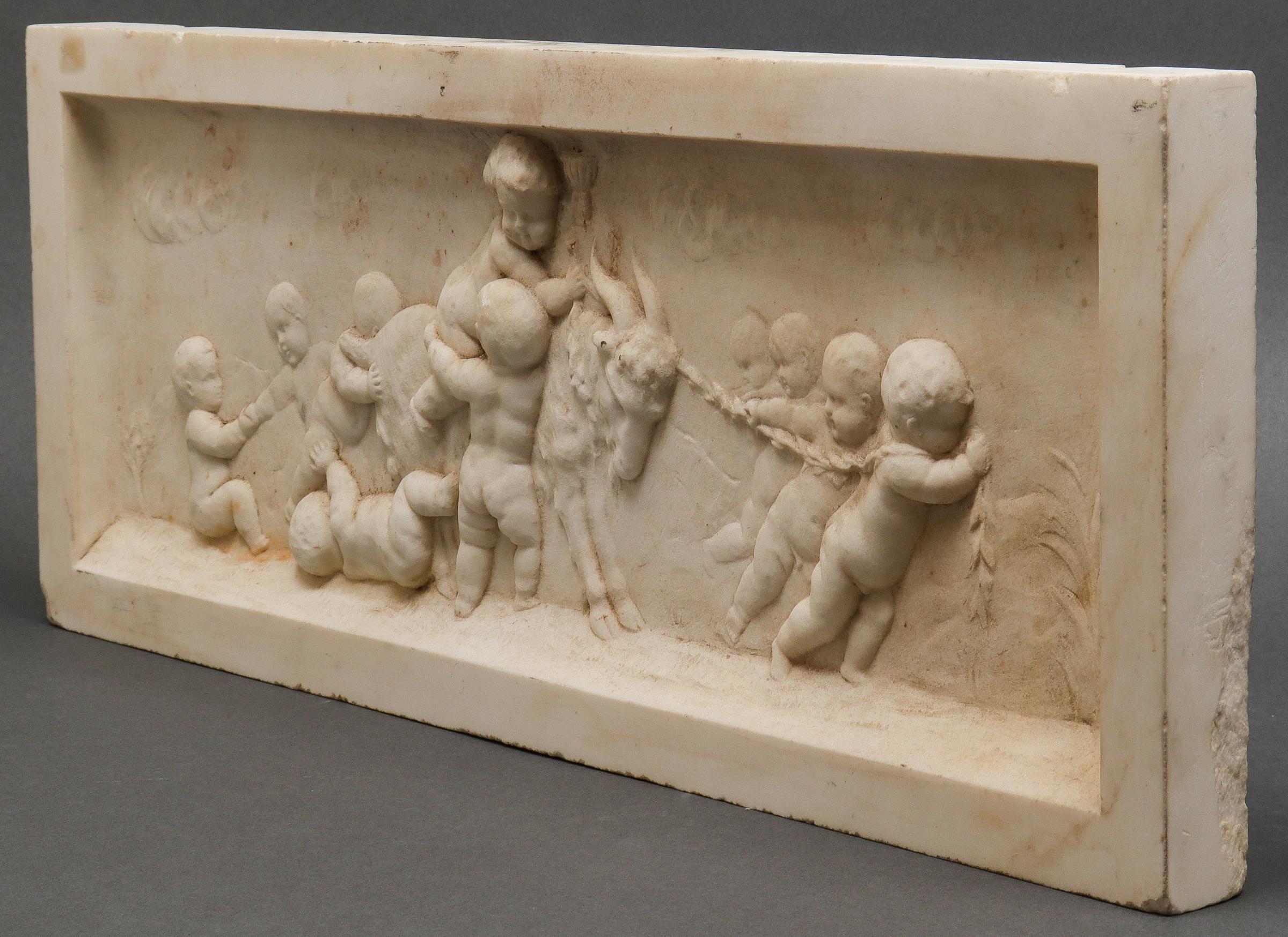 Neoclassical carved marble architectural relief or frieze plaque with a bas-relief scene depicting playful cherubs leading a goat. In great antique condition with age-appropriate wear.