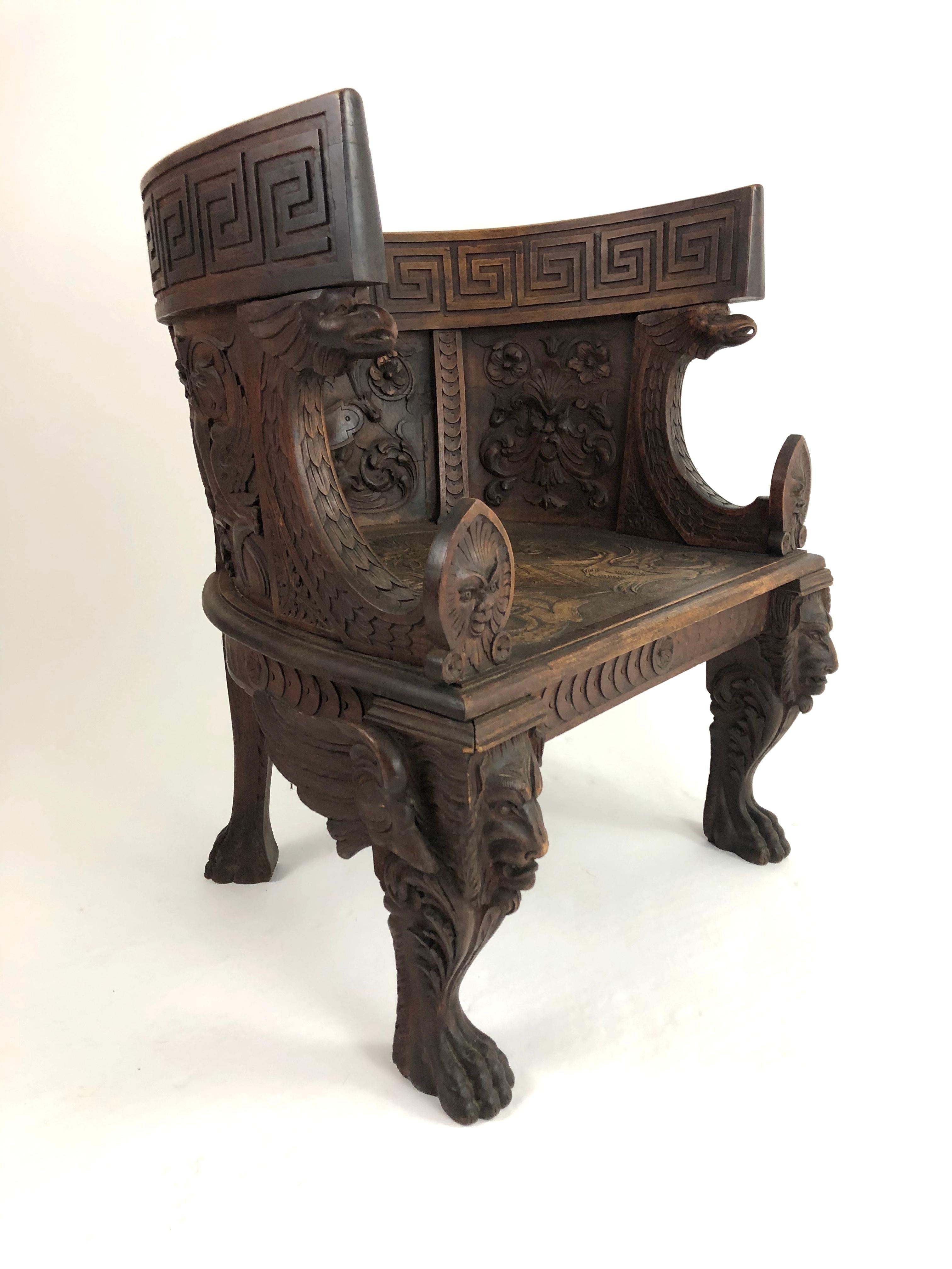 A highly sculptural, architectural and decorative neoclassical style carved walnut Grand Tour throne-like arm chair, richly carved overall, with a band of Greek key decoration at the top over panels with floral and foliate decoration above the seat