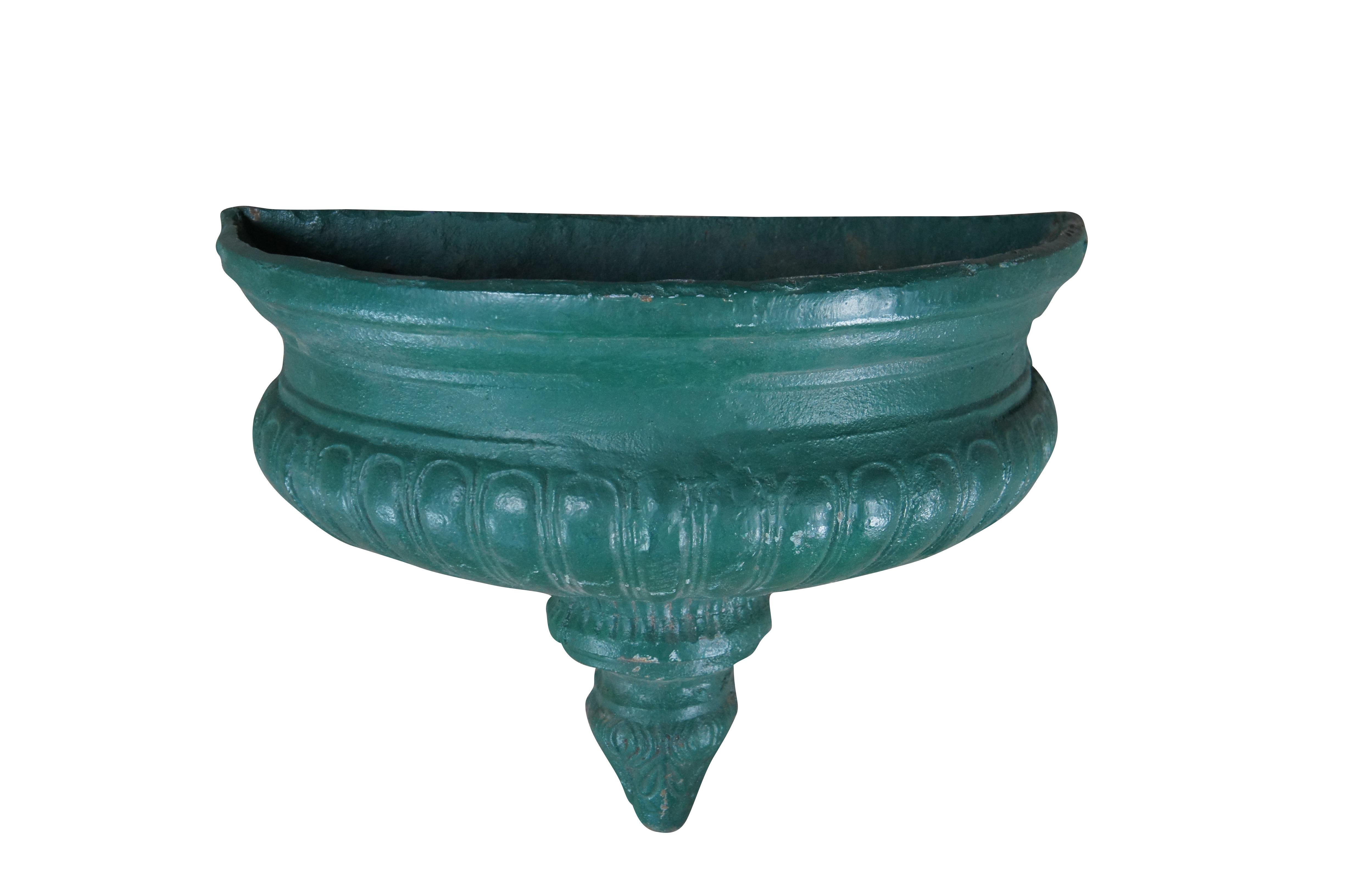 Heavy cast iron wall hanging fountain bowl / planter / garden urn. Demilune / half round shape with fluted Neoclassical styling and an acanthus foliate drop finial.

Dimensions:
22.5