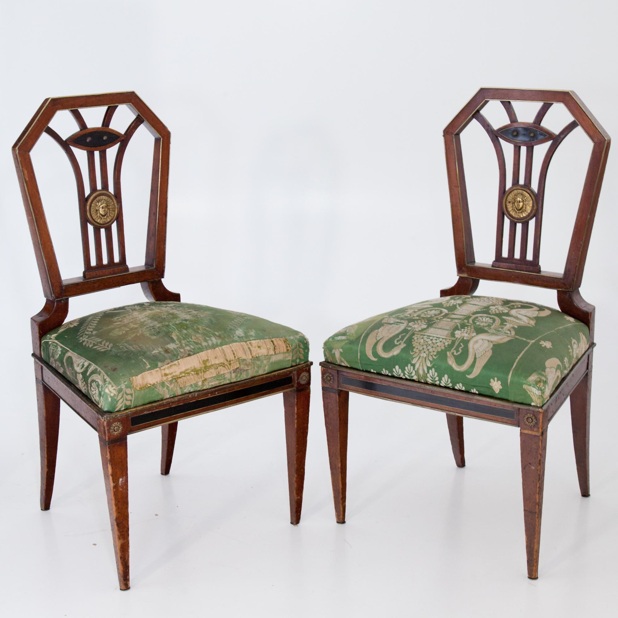 Two Empire chairs in museum quality, probably by Gottlieb August Pohle, Vienna, circa 1805-1810. Mahogany frame with brass applications and rung backrests. Partly original wallpapering.