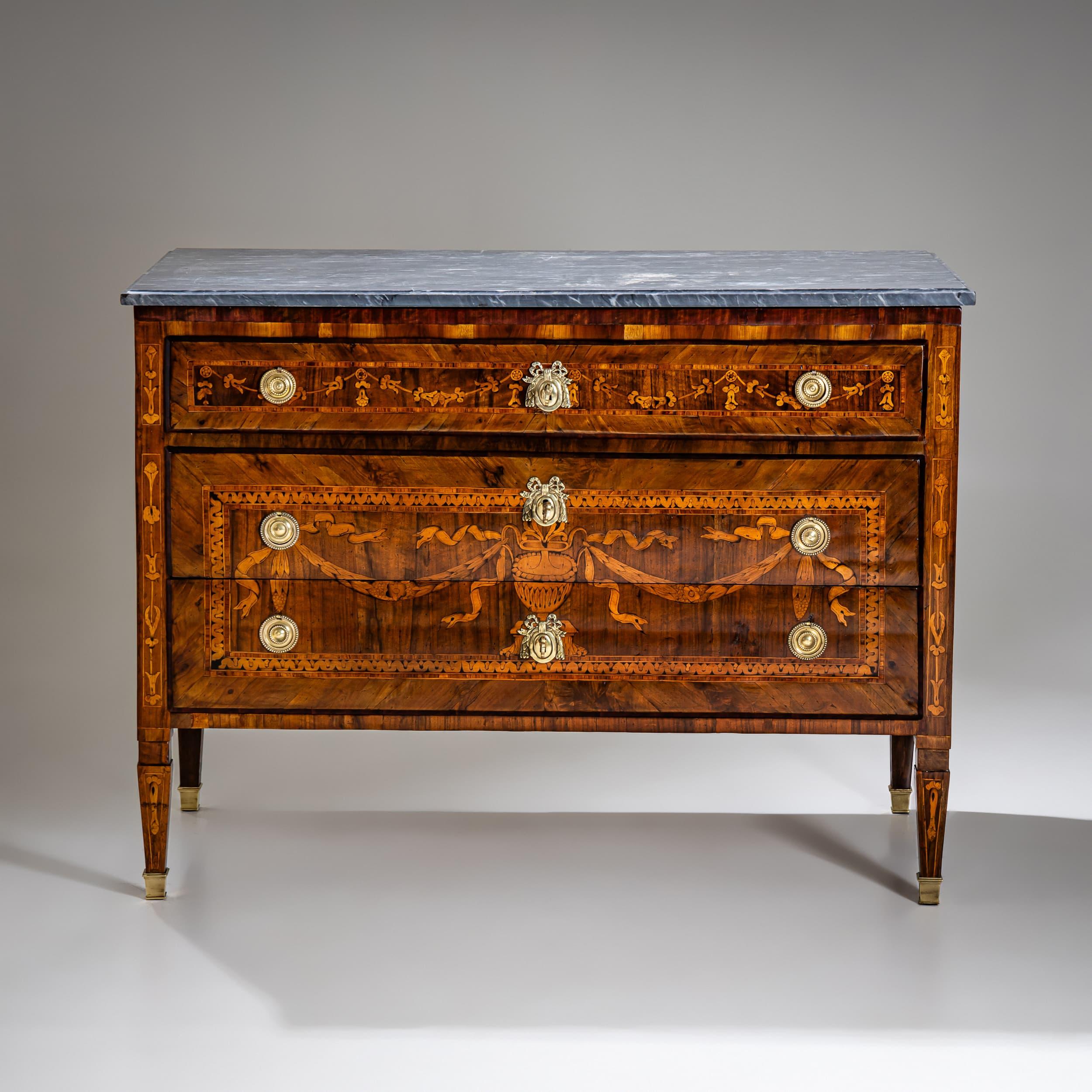 Neoclassical chest of drawers with three drawers, standing on tapered square legs with refined brass sabots. The original top is made of gray marble with white veining, lending the piece a distinguished appearance. A horizontal divider separates the