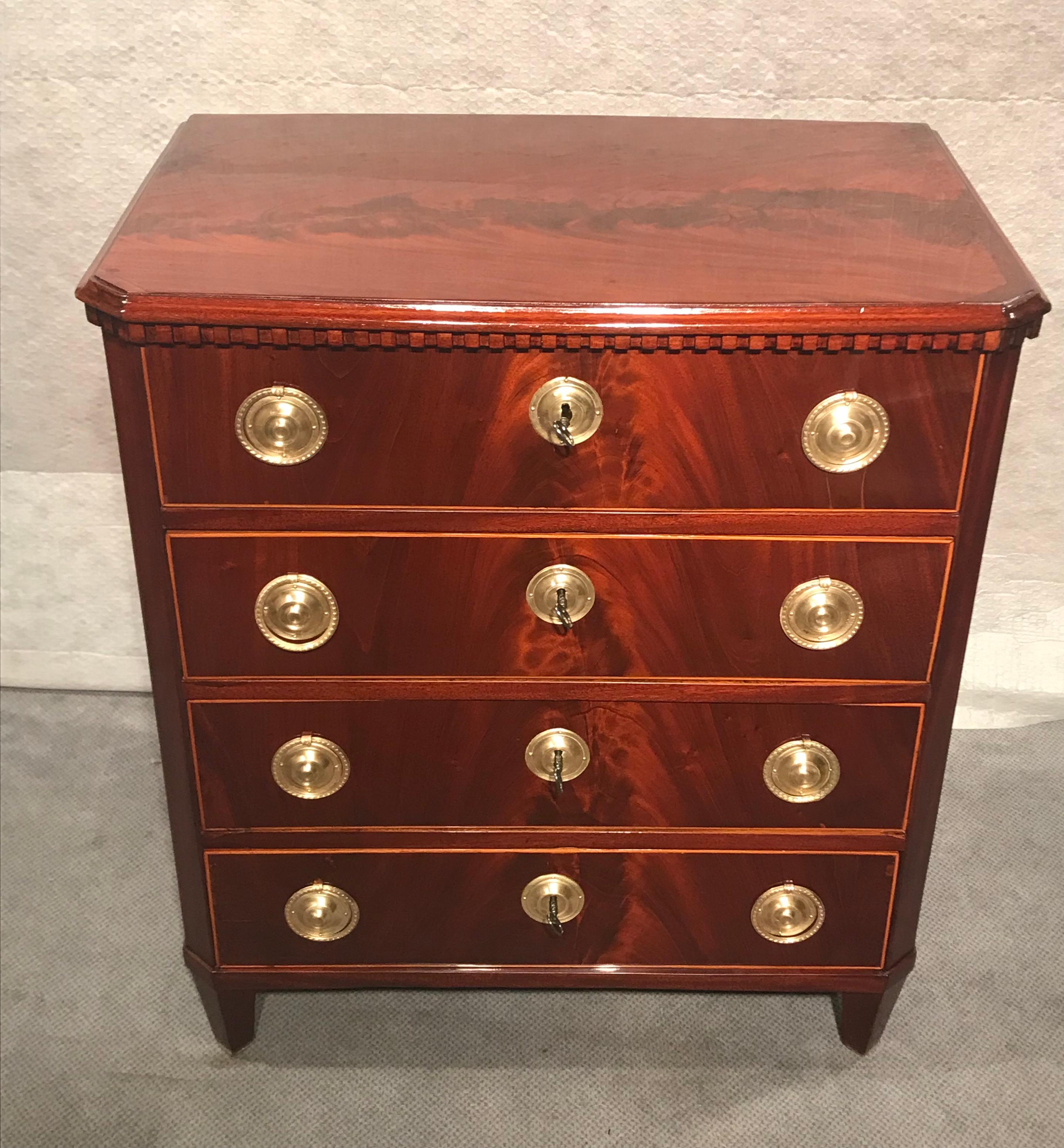 This neoclassical chest of drawers offers you a lot of storage space. The elegant chest of drawers dates back to around 1800 and comes from Northern Germany. It has a beautiful mahogany veneer and and 4 drawers. The top has a pretty dentil panel