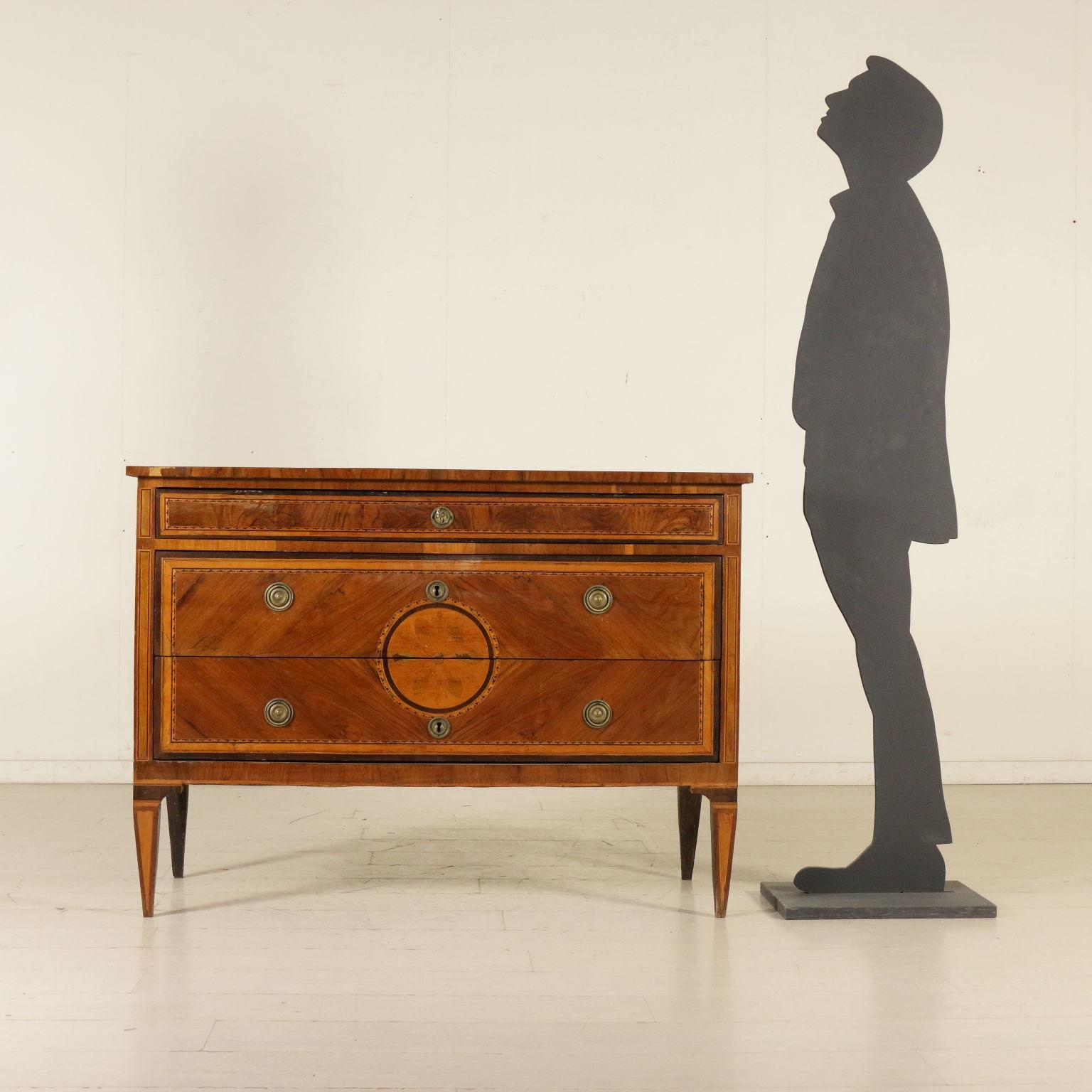 An elegant neoclassical chest of drawers, pyramidal legs. Two drawers with rose in the middle, quadripartite, plus a small drawer under the top. Cathedral walnut veneered reserves with inlaid threads. Top with inlaid rose. Maple and wood.
