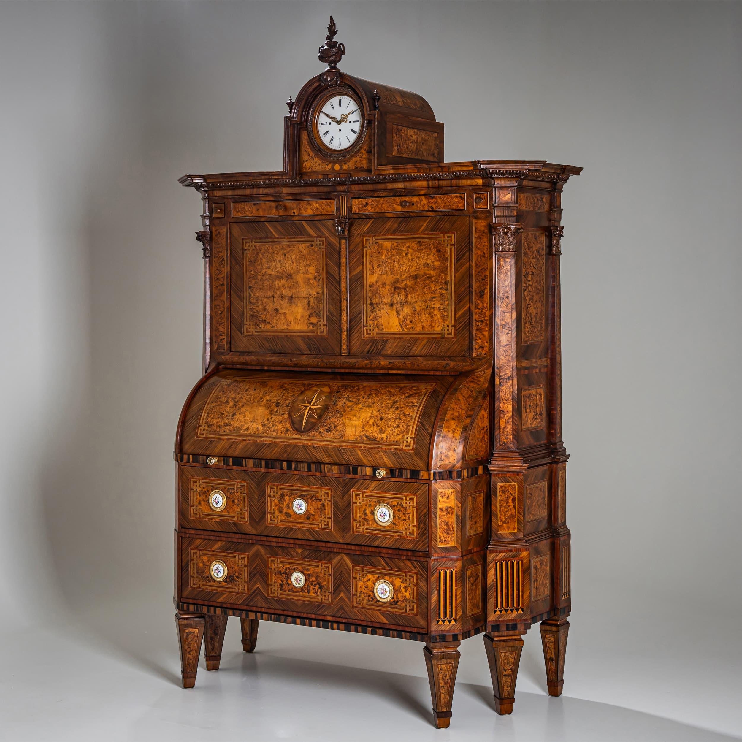 Significant neoclassical cylinder secretary resting on six tapered square legs, canted at the corners. The lower commode section, with two drawers, projects slightly in a risalit form and is adorned with circular porcelain plaques featuring