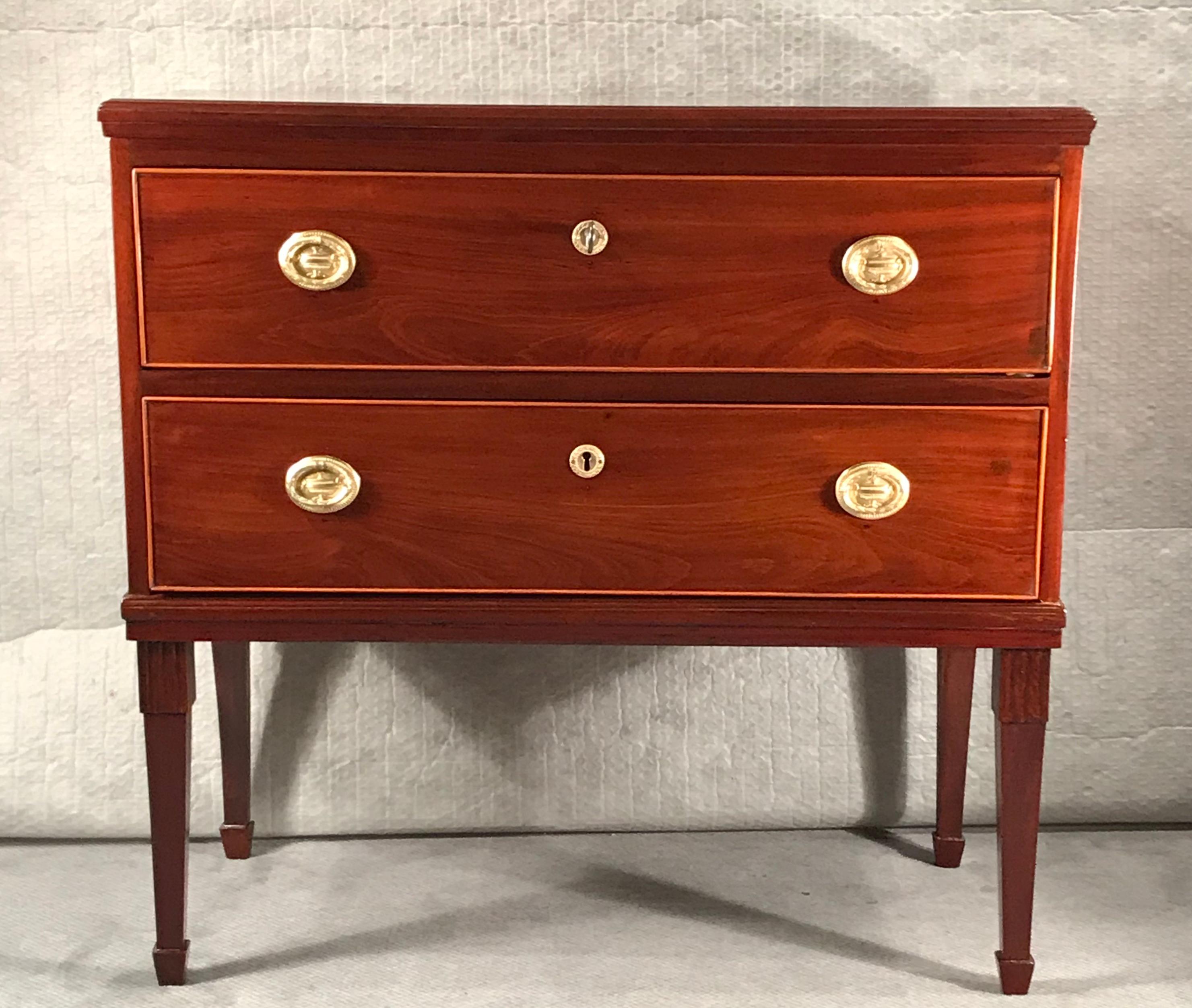 Neoclassical dresser, Northern Germany, 1800.
This elegant dresser has an exquisite mahogany veneer. It stands on four slender legs and has two spacious drawers. The top is additionally decorated with a satinwood inlay. This chest of drawers would