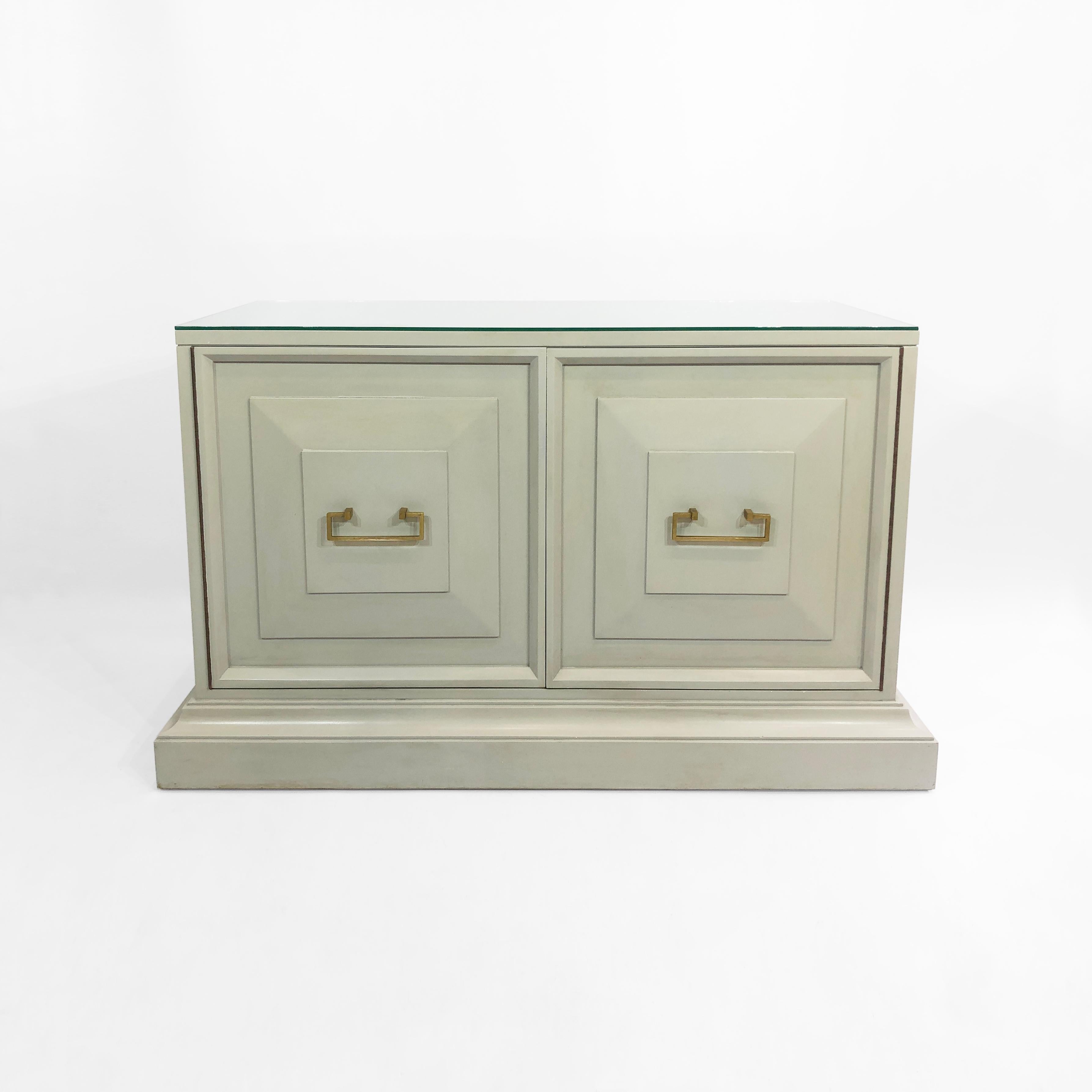 An elegant yet robust cabinet in a light duck egg blue sits atop a plinth in this stunning neoclassical inspired piece from ‘70s America. There are elements of chinoiserie in the design of the cabinet. The hinges are made of brass, whilst the
