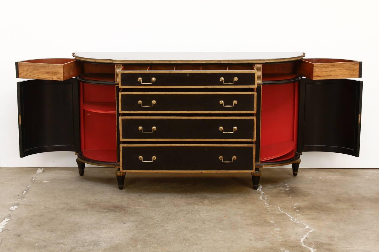 Dramatic ebonized and parcel gilt buffet or sideboard made in the manner of Maison Jansen. Decorated with brass lattice embellishments and trim in the Directoire neoclassical taste. Produced by famous Los Angeles, CA retailer Barker Bros. The case