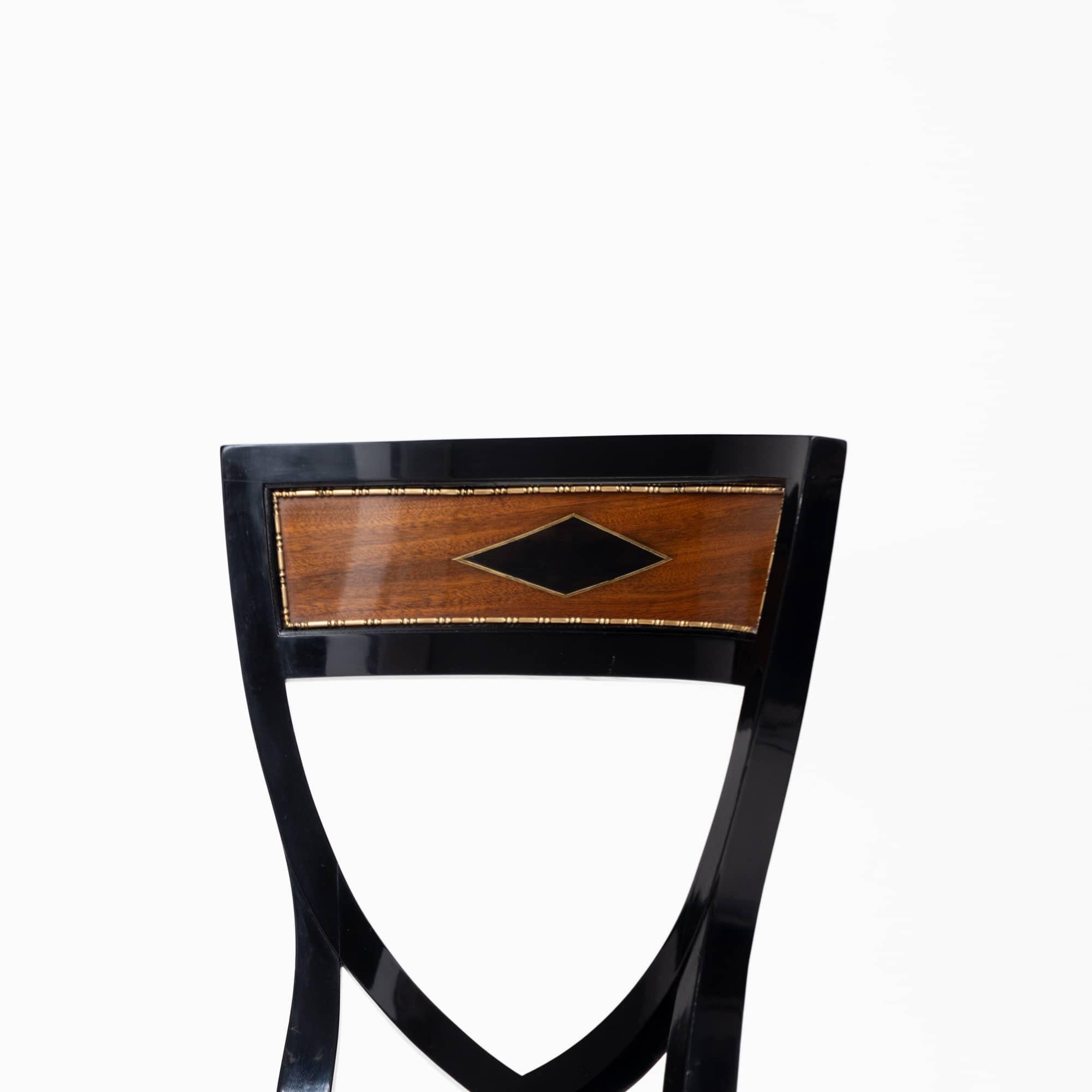Side chair with a shield-shaped backrest and an ebonized frame boasting elegant sabre legs. The backrest is highlighted with brass profiles and veneered in rich walnut, adding a touch of sophistication. The seat has been newly upholstered and