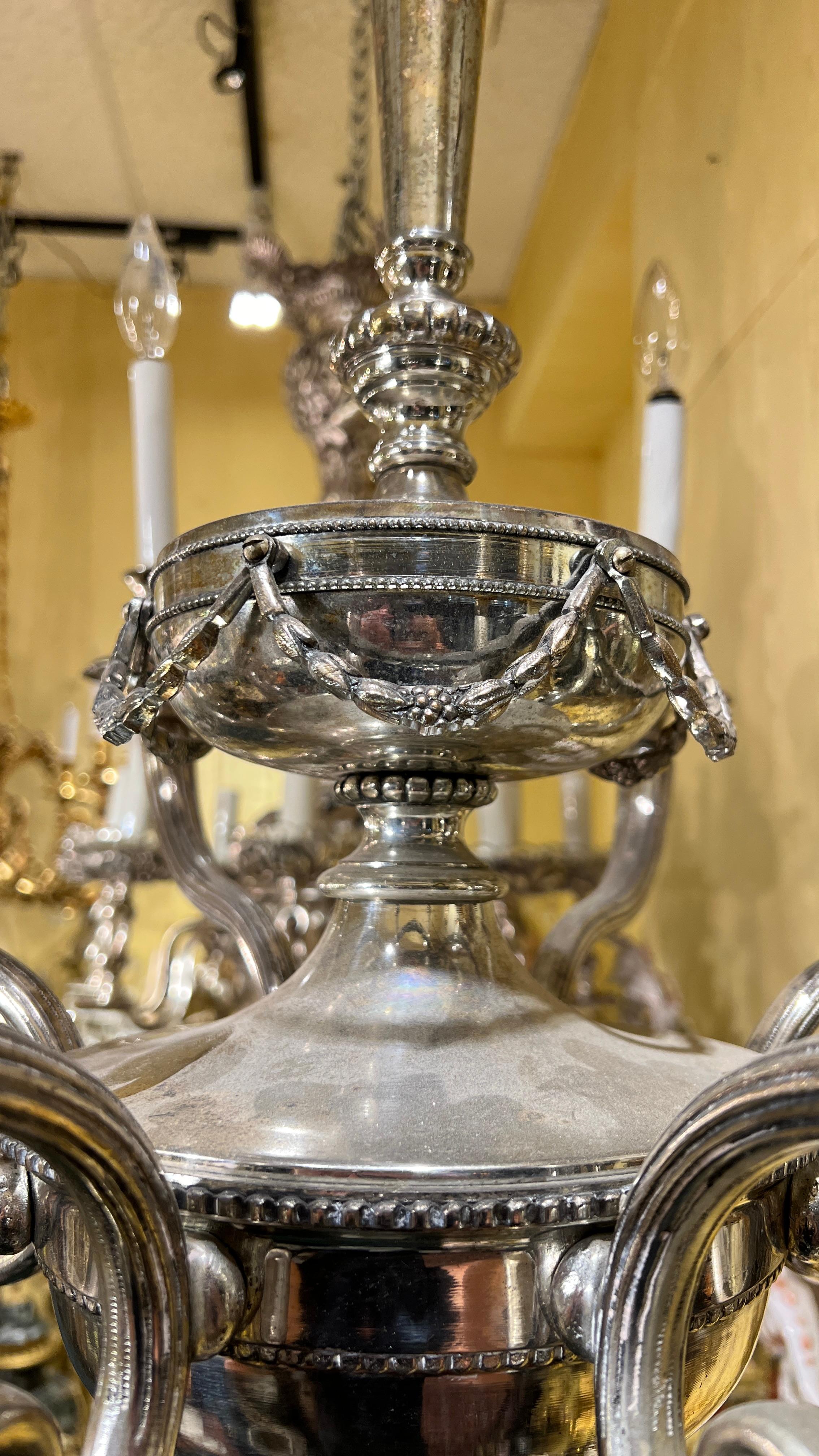 A fine silvered chandelier in the neoclassical style, attributed to Edward F. Caldwell, with candelabra size sockets, candle covers and wiring, ready for use.
