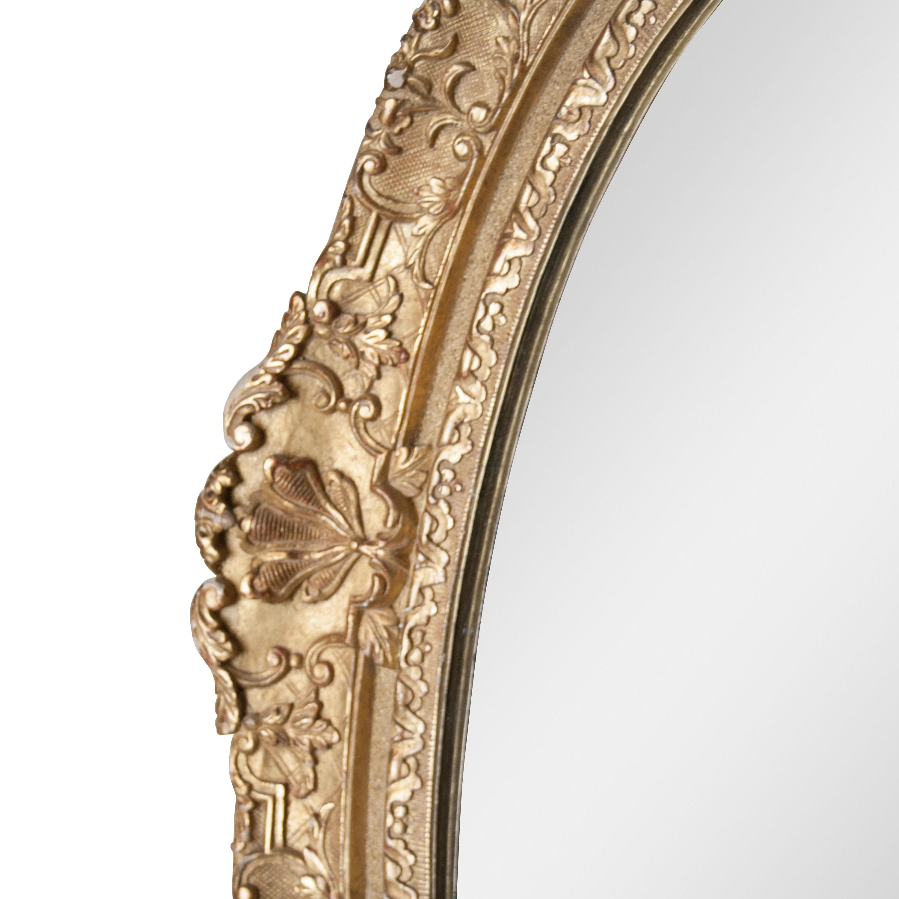 Miroir artisanal de style néoclassique Empire. Structure en bois sculpté à la main de forme ovale avec finition en feuille d'or.
 