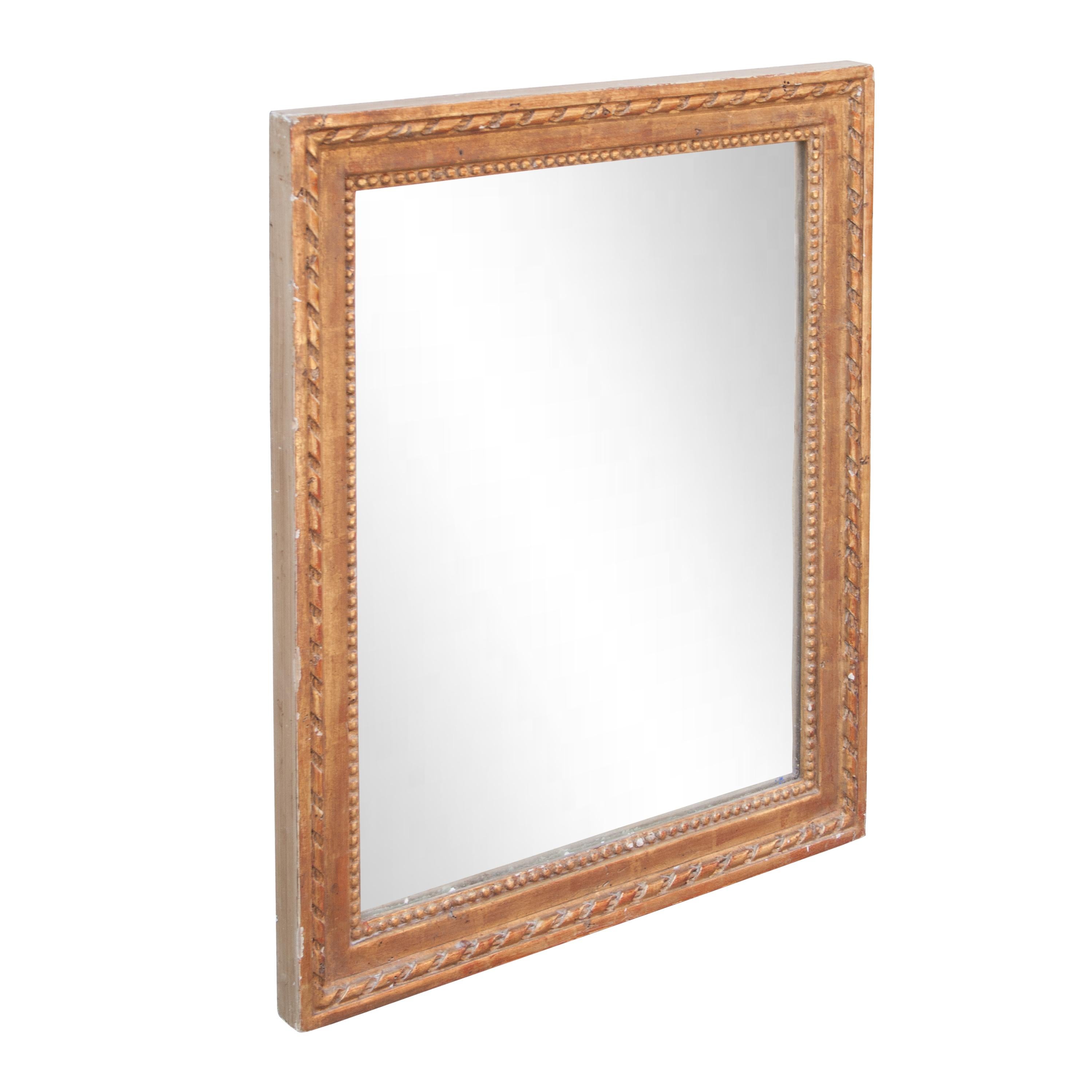 Miroir artisanal de style néoclassique Empire. Structure rectangulaire en bois sculpté à la main avec une finition en feuille d'or.