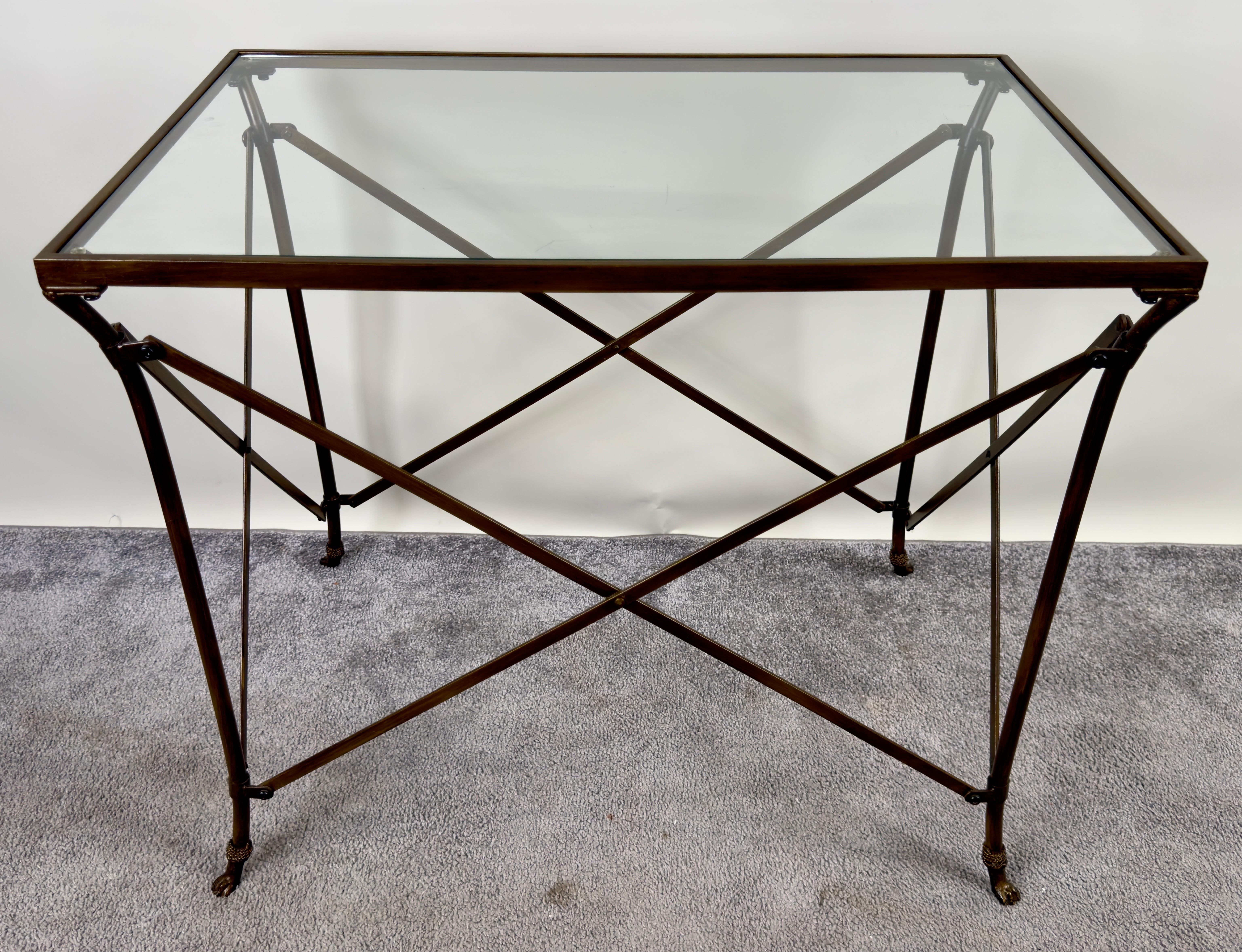 This classic Neoclassical French Empire style side serving table  features a refined rectangular glass top supported by slender bronze legs. The legs, adorned with graceful paw feet, exude a timeless sophistication. These are further connected by