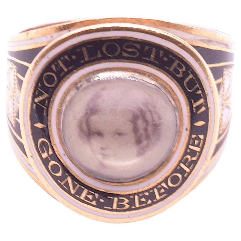 This spectacular mourning band is of black enamel with accents of white enamel and bordered in gold accents. With its breathtaking miniature painting of a young girl, this ring is a fine example of the neoclassical influences of the Georgian period