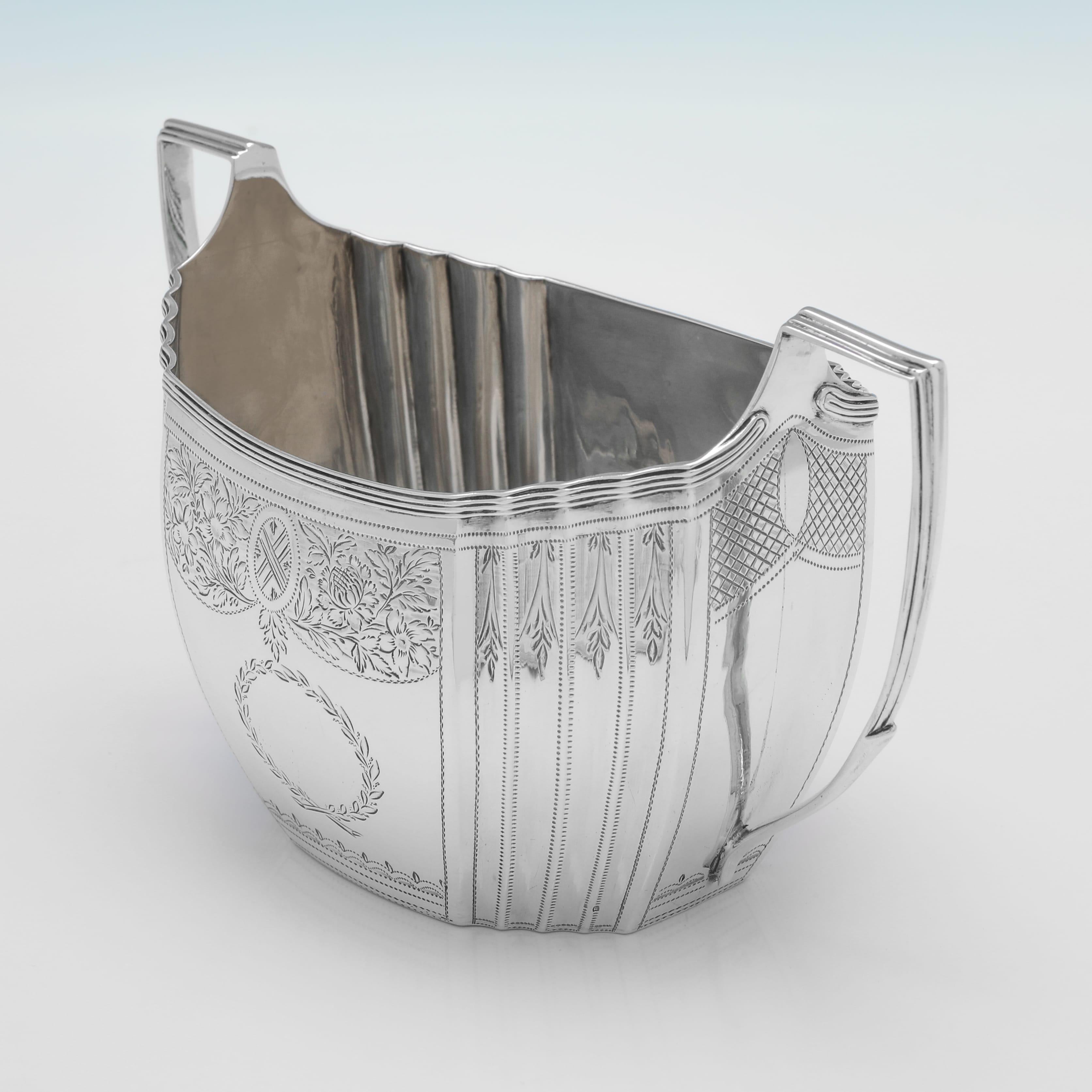 Hallmarked in London in 1803 by Samuel Godbehere, Edward Wigan & James Boult, this handsome, George III, Antique Sterling Silver Sugar Bowl, features shaped sides, engraved decoration, and reed borders. The sugar bowl measures 4.25