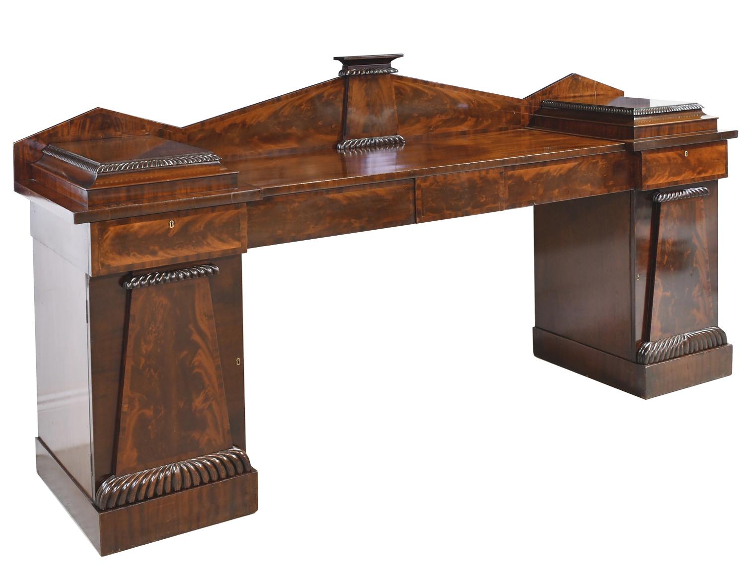 A very long and elegant American Federal, pedestal sideboard in mahogany with mahogany inlaid bandings along the borders. Inspired by the classical architecture of ancient Greece and Rome it has a gadrooned sarcophagus design on the doors and on the