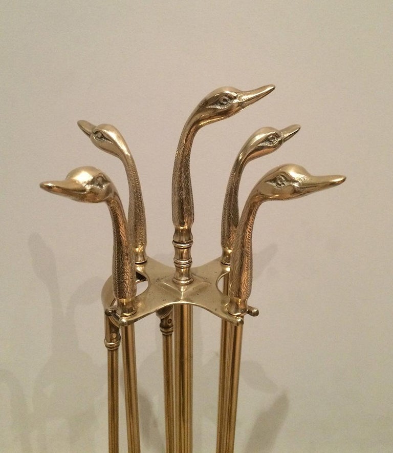 This set of neoclassical fireplace tools on stand are made of brass and iron. They are displaying duck heads. This is a French work, in the style of Maison Jansen, circa 1960.