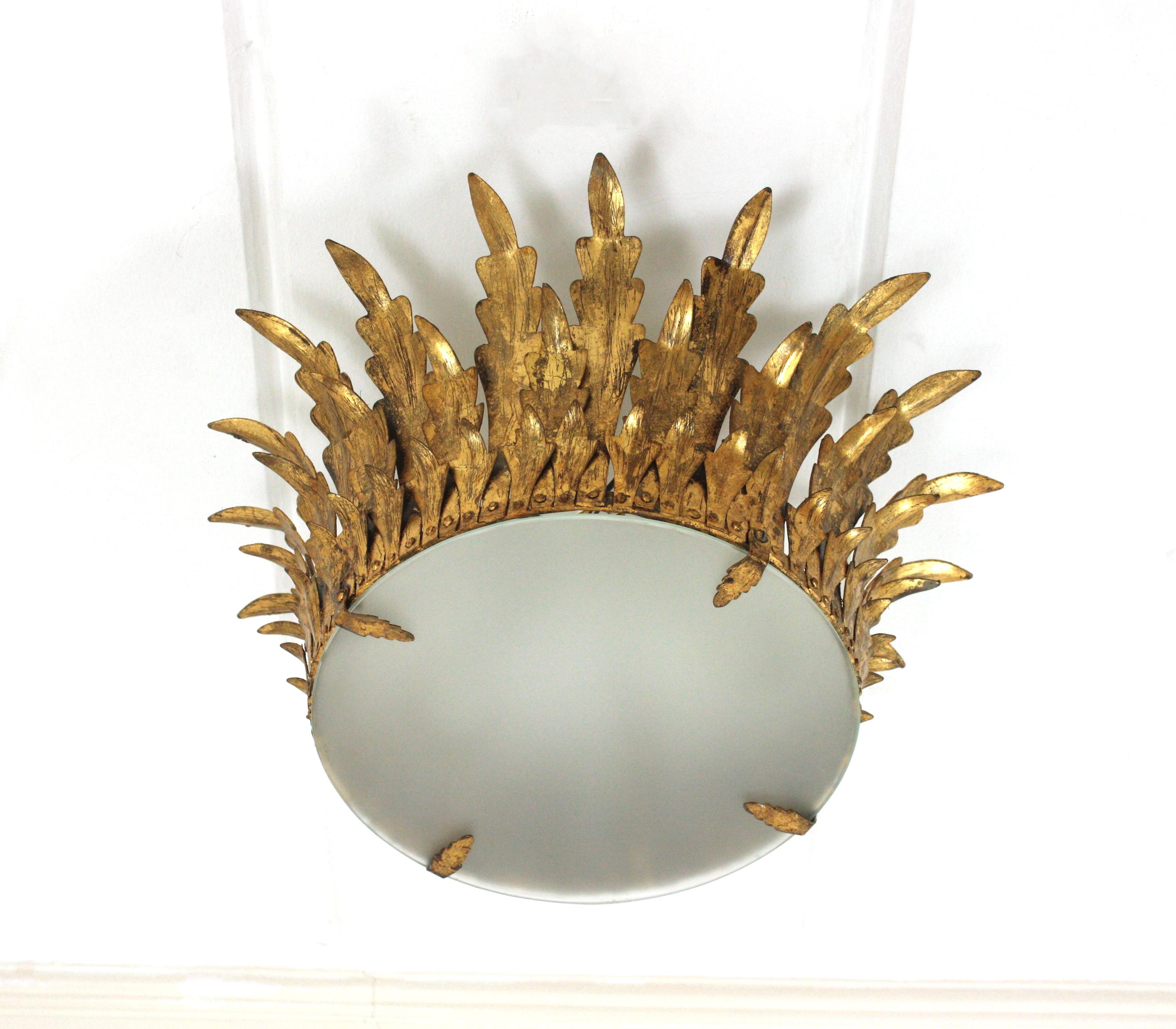 Triple Layered Foliage Crown Shaped Ceiling Light Fixture / Pendant, Spain, 1940s.
This flush mount features three layers of leaves hand-crafted in gilt iron surrounding a central frosted glass difuser creating a sunburst or crown shape.