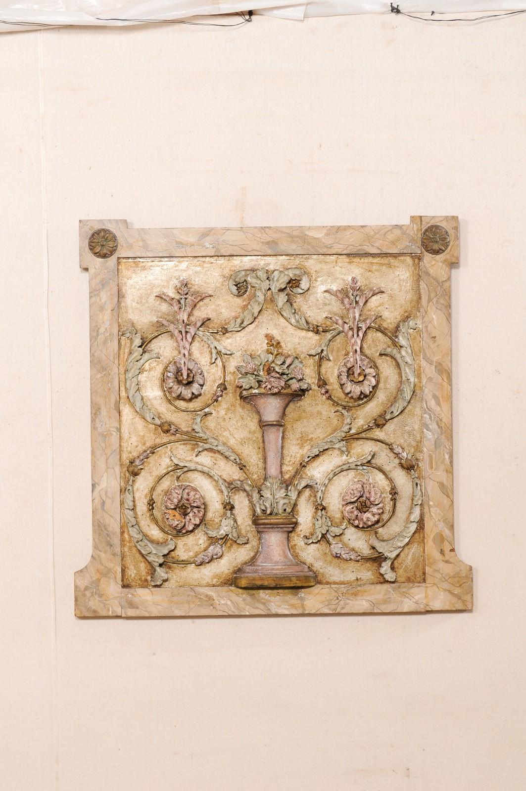 A French carved-wood wall plaque from the early 19th century. This antique wall decoration from France features the Neoclassical stylings of swirling leaves and florals splaying outward from the urn center. All set within a 42