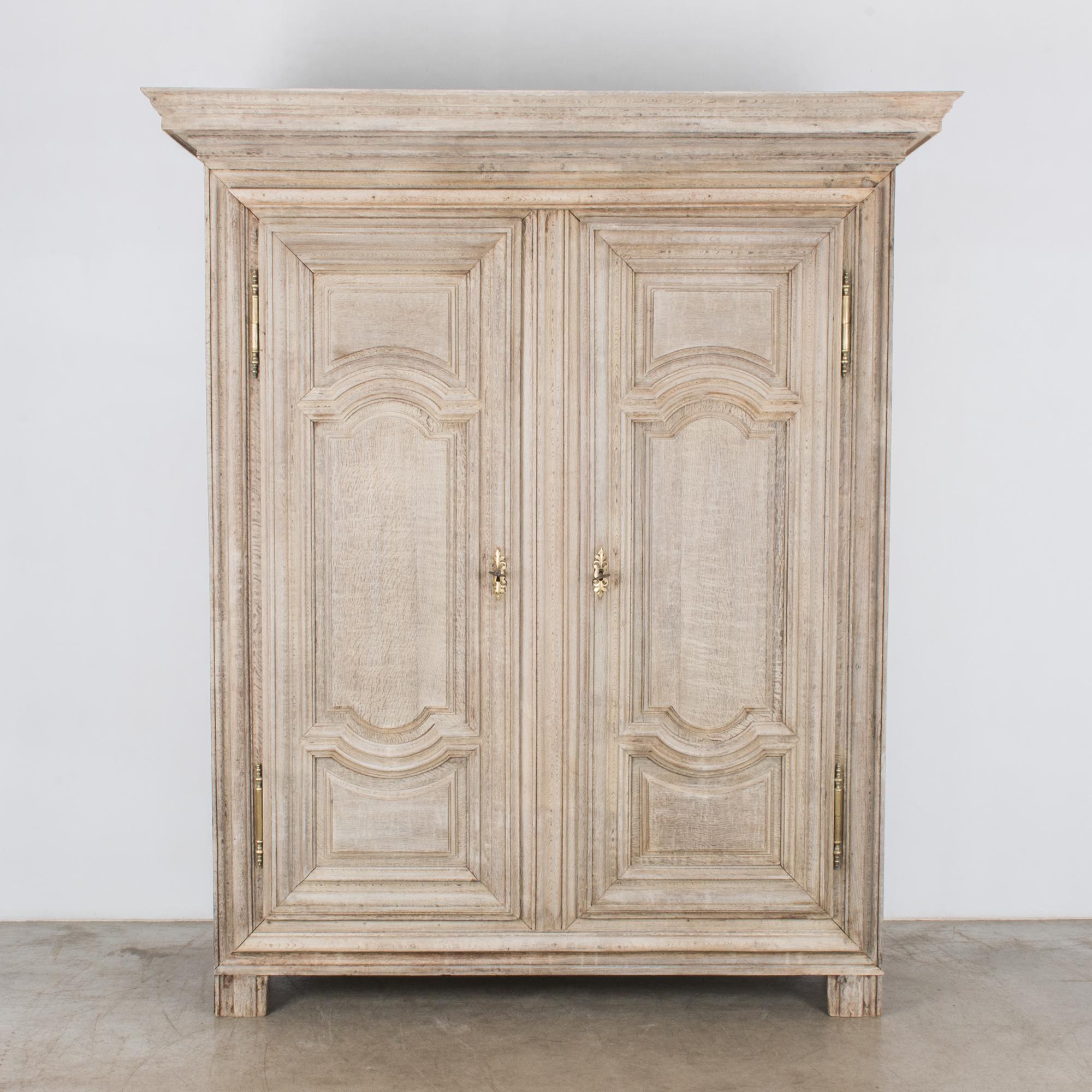 This bleached oak armoire was made in France, circa 1800. The two doors, each with its own key, open to reveal the generous storage space with three shelves. Elevated slightly on rectangular posts, this cabinet features decorative hinges and elegant