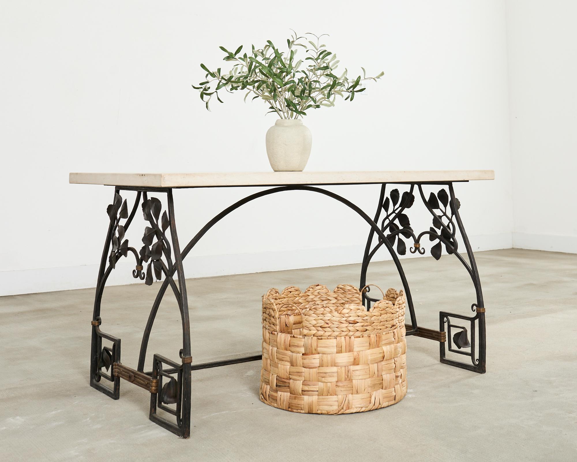 Stylish 20th century wrought iron patio and garden dining table featuring a thick French limestone top, The trestle base is crafted in the decorative arts taste with gracefully curved legs and stretchers ending with neoclassical Greek key feet. The