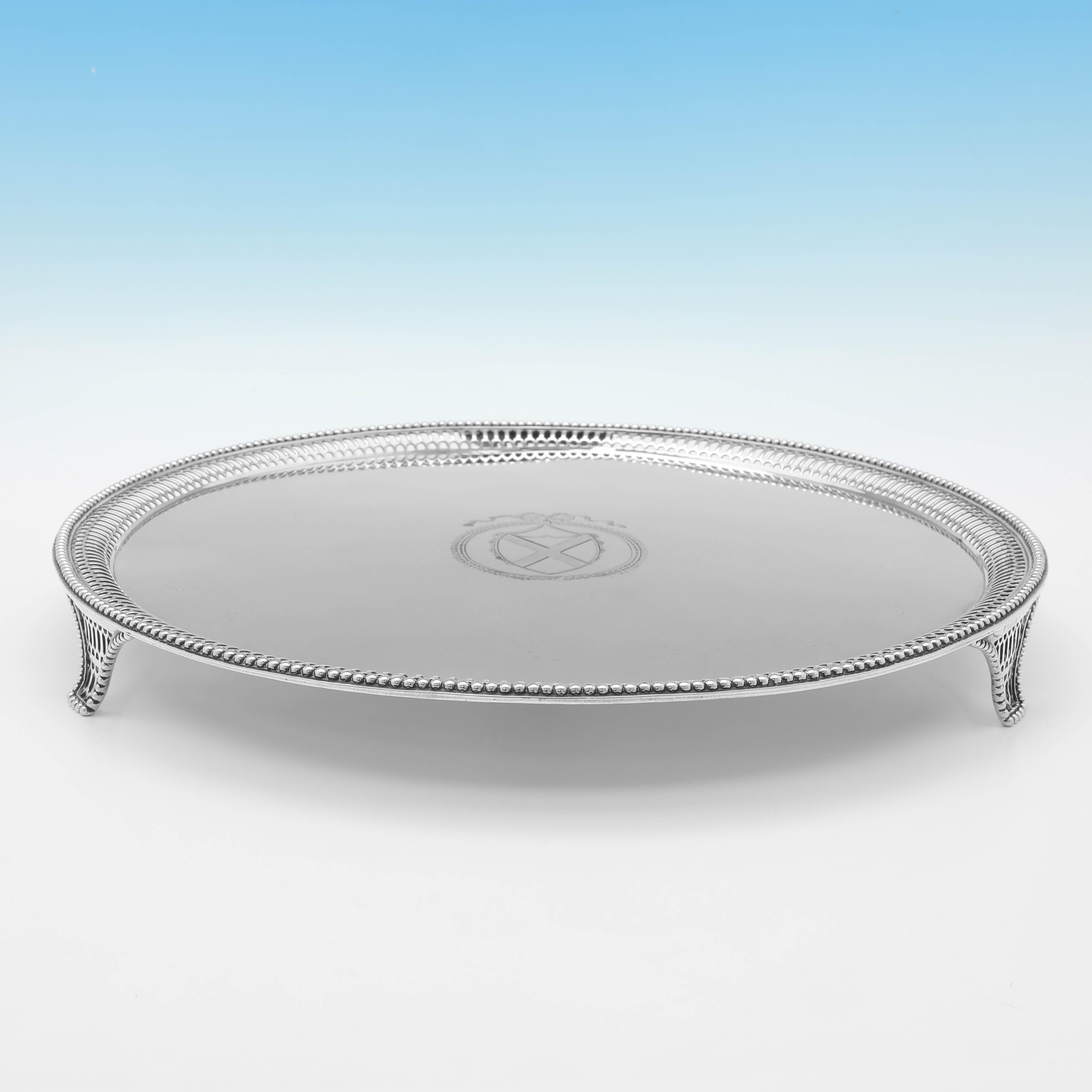 Hallmarked in London in 1774 by John Carter II, this handsome, George III Period, antique sterling silver salver, stands on 3 feet, and features a pierced rim and bead border, and an engraved shield to the centre. 

The salver measures 1.5