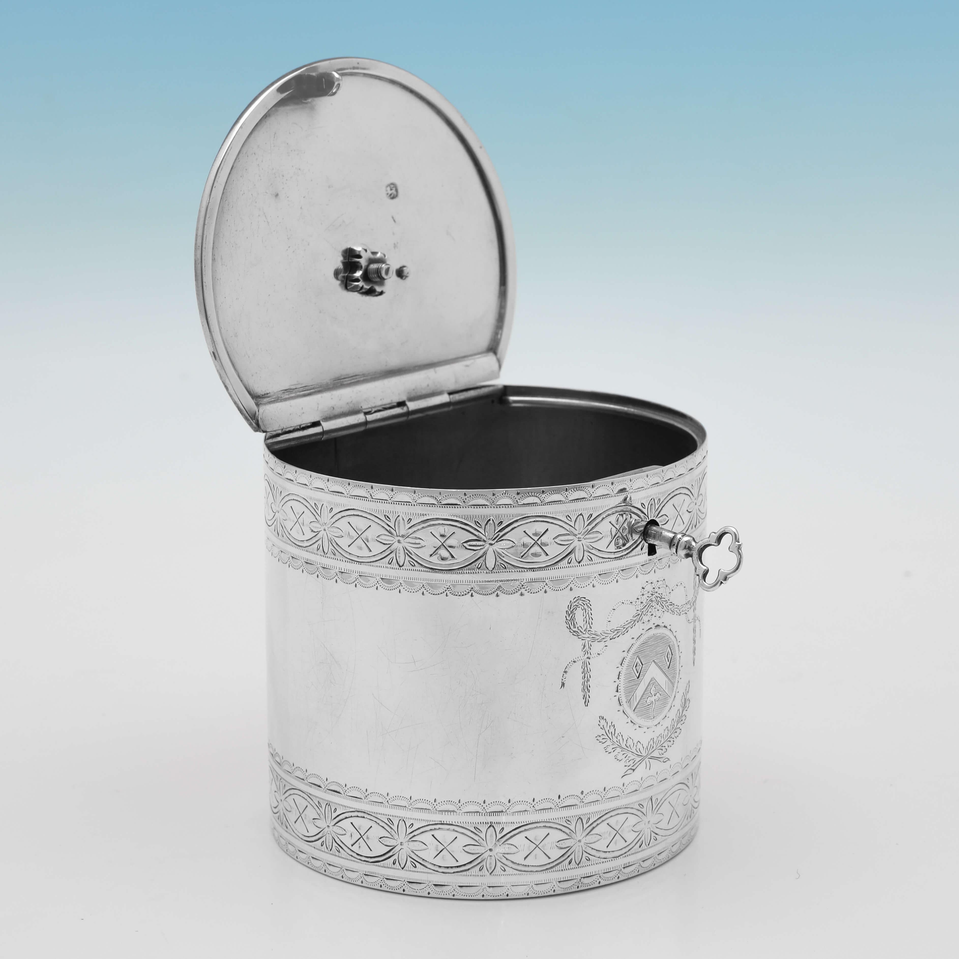 Hallmarked in London in 1775 by Walter Brind, this charming, George III period, Antique, Sterling Silver Tea Caddy, is cylindrical in shape, with wonderful engraved decoration to the body and lid, the original key, and an engraved armorial to the