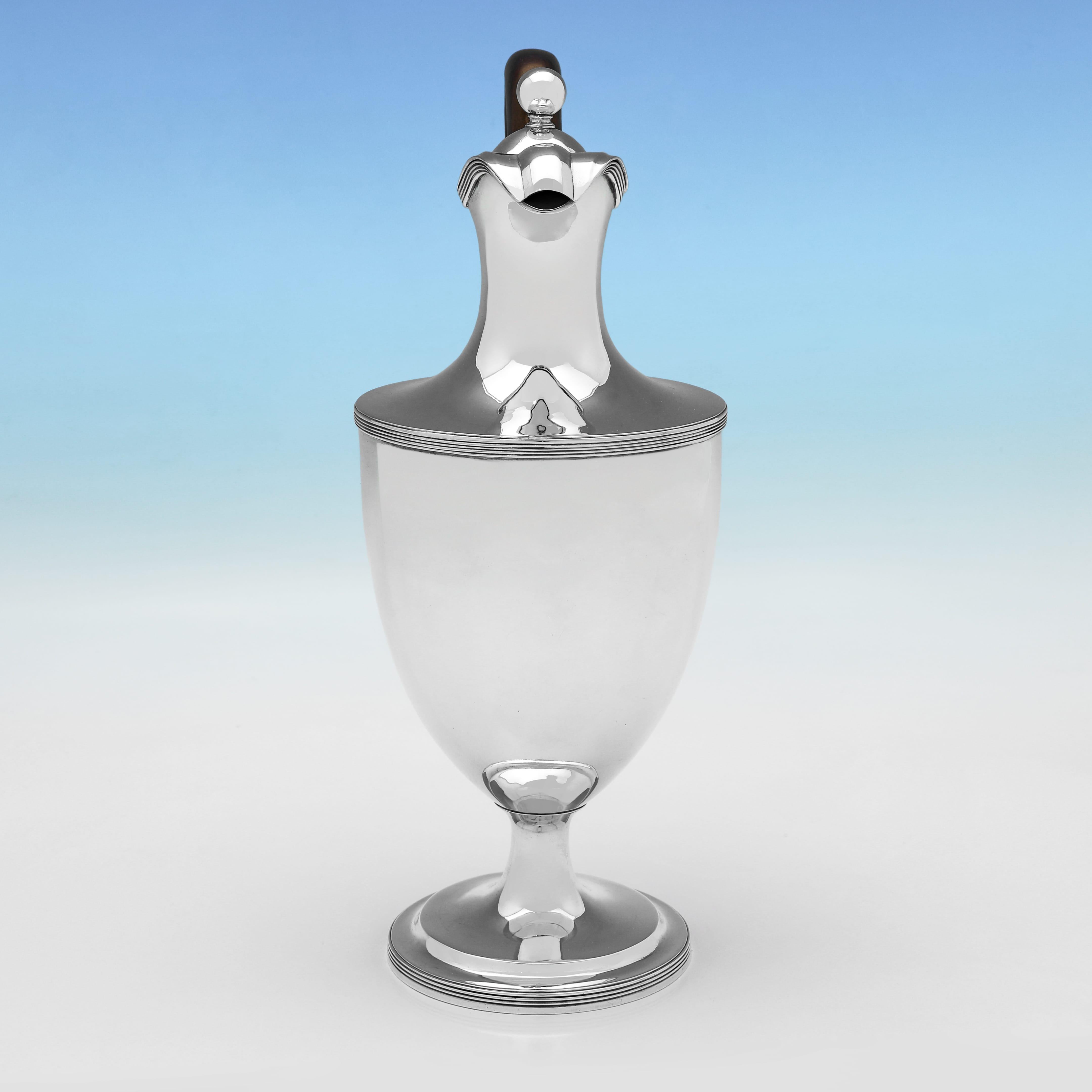Marcada en Londres en 1800 por William Bennett, esta hermosa jarra de vino de plata de ley de la época de Jorge III es de diseño sencillo, con bordes de caña y asa de madera. El aguamanil de vino, o jarra de agua caliente, mide 29 cm de alto, 15 cm