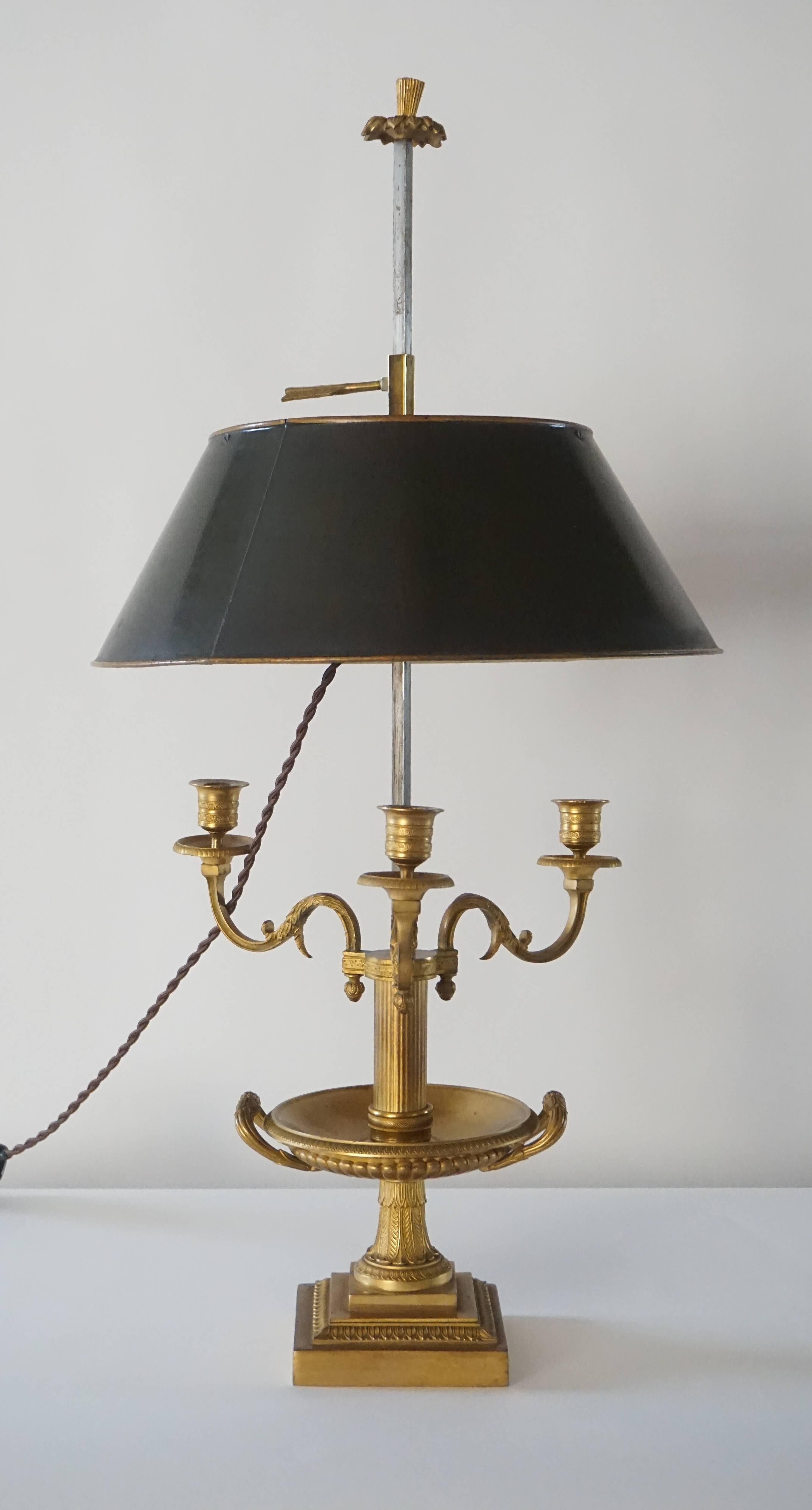 French Directoire, early Empire period gilt bronze bouillotte lamp having fluted tazza-form base issuing three scrolling candle arms and thistle-finial topped steel standard with round green tole shade.  Electrified socket-cluster can easily be