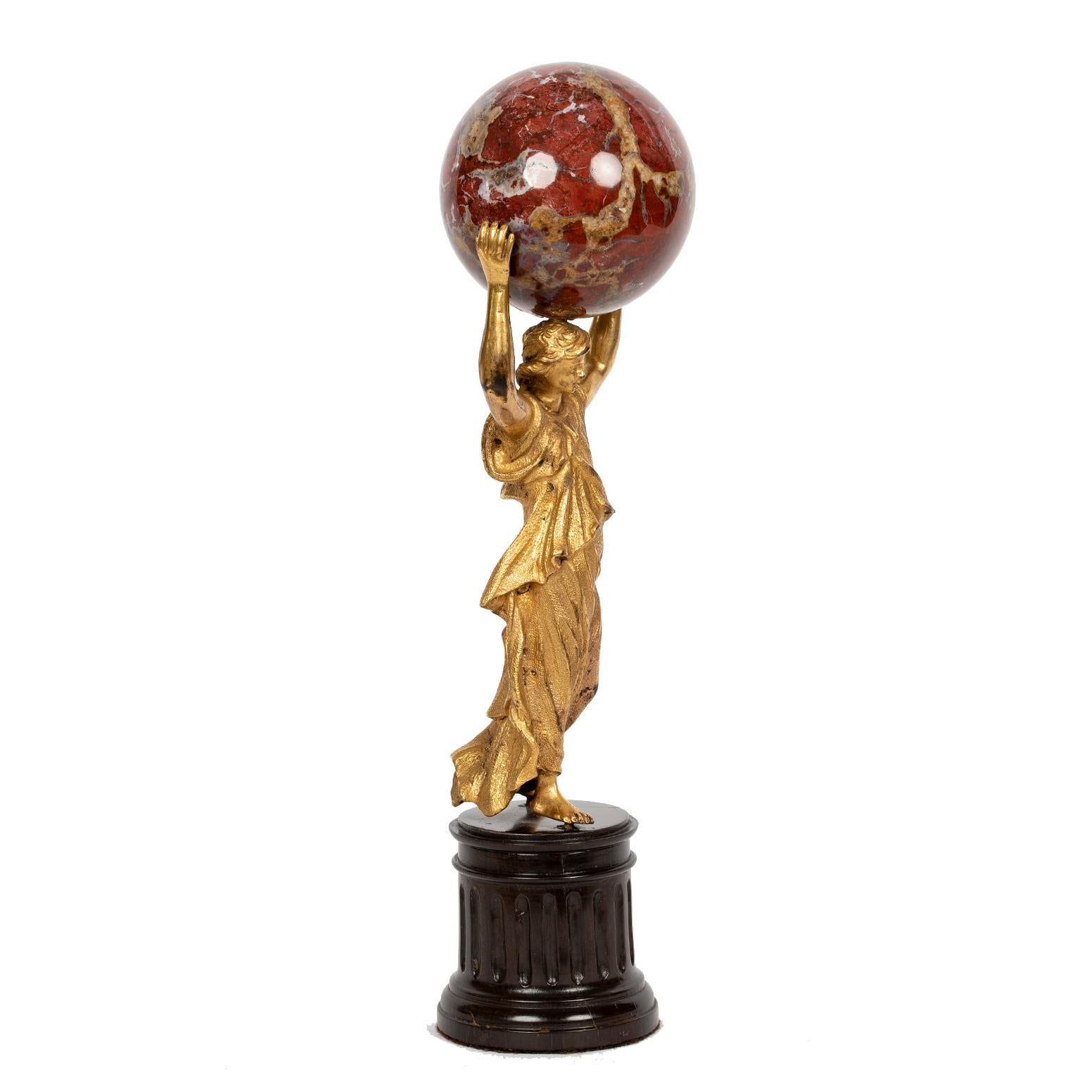 A gorgeous Continental classical gilt caryatid figure on a dark wood column base, holding a rouge marble ball (attached).