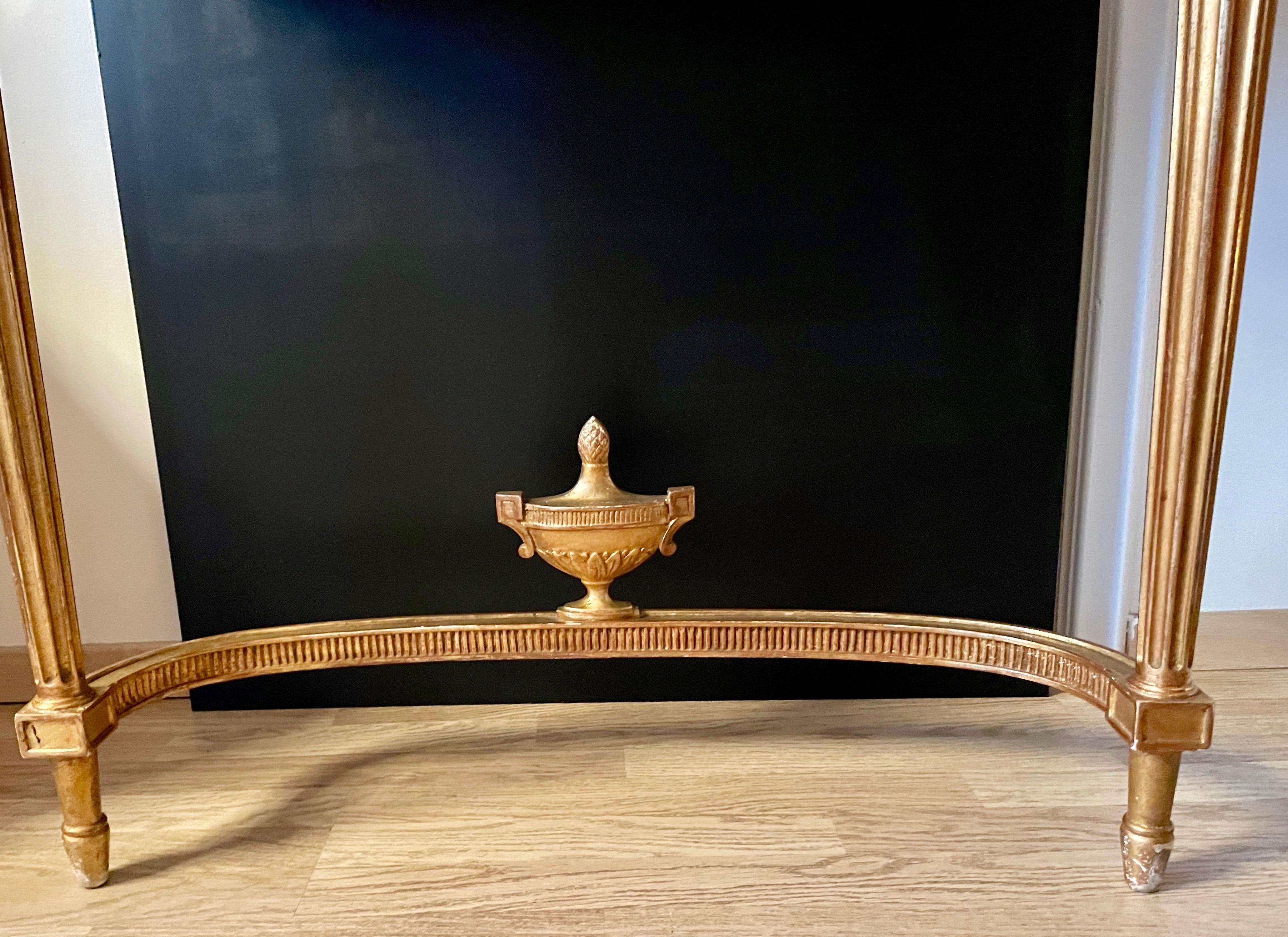 Elegant gild wood console table with a urn at the base.
Mirror under the black lacquered top.
The back is also in black lacquered wood.
Labeled les ateliers R.G.Paris France.
C.1950.