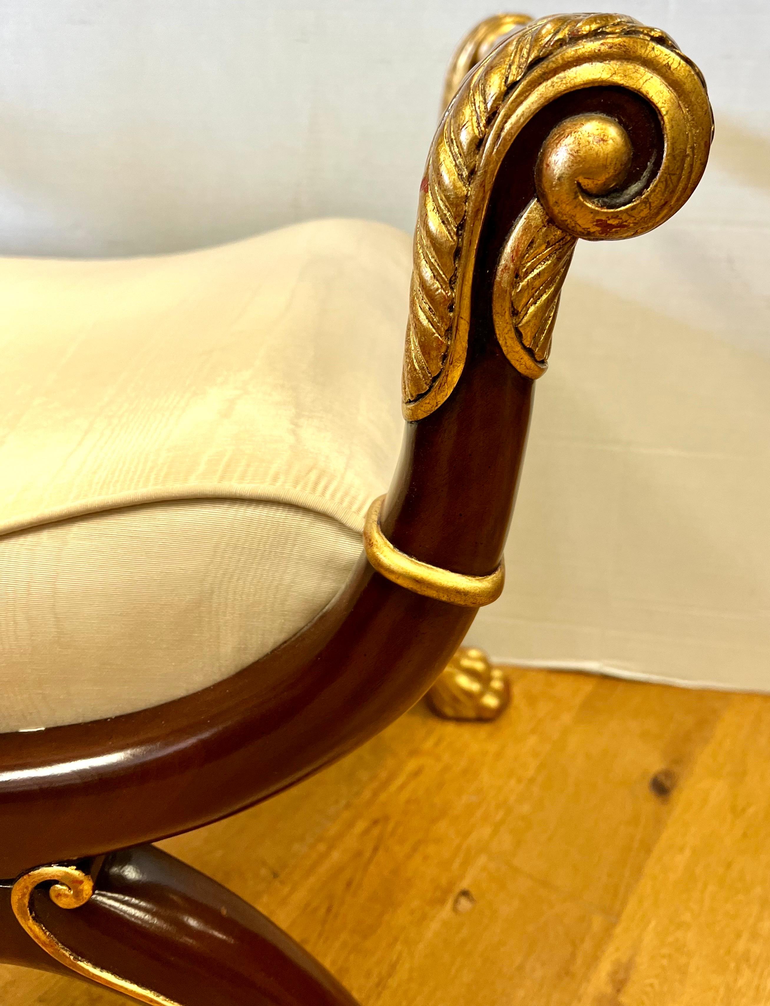 Elegant neoclassical style mahogany and giltwood bench with x-base terminating in paw feet. Upholstery is a cream silk.