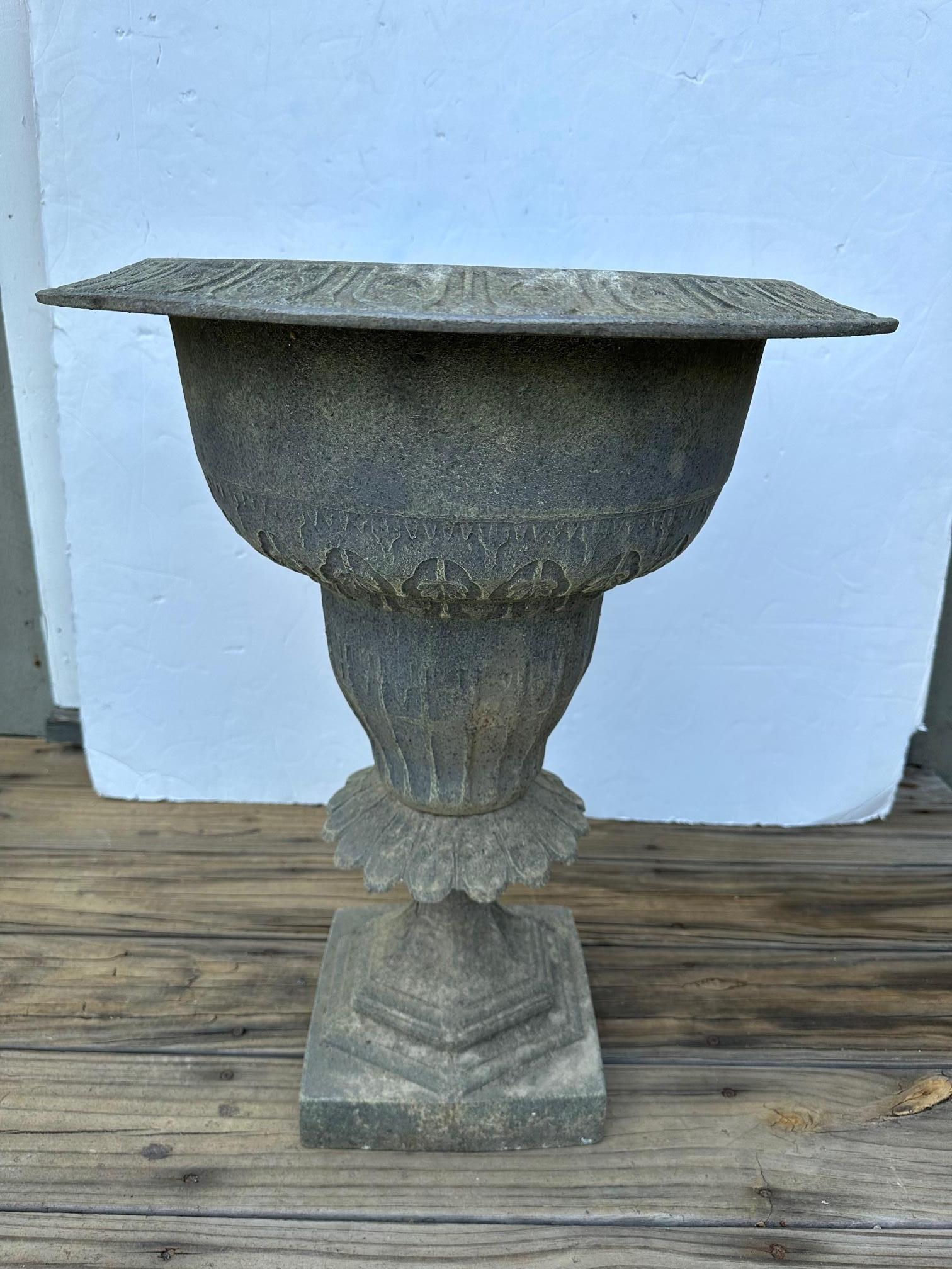 Lovely vintage gray metal round urn planter having neoclassical designs around the top periphery and 9