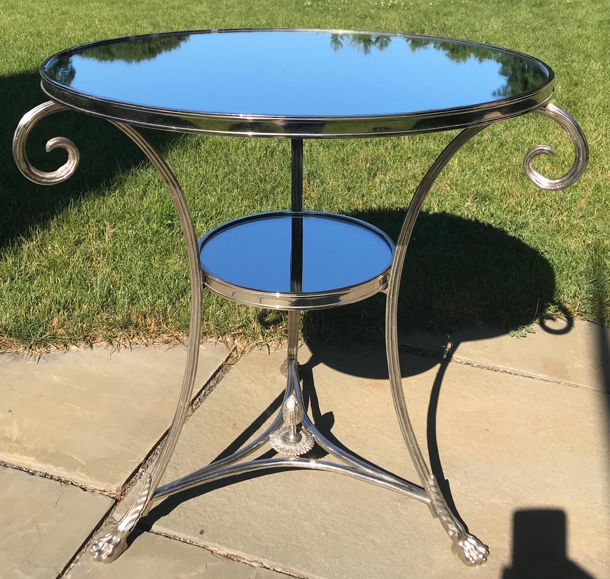 A wonderful rare French neoclassical round chrome plated bronze gueridon with mirror top. Scroll arms ascent the sides ending in claw caster feet.
The table has a second shelf and a centre finial.
  