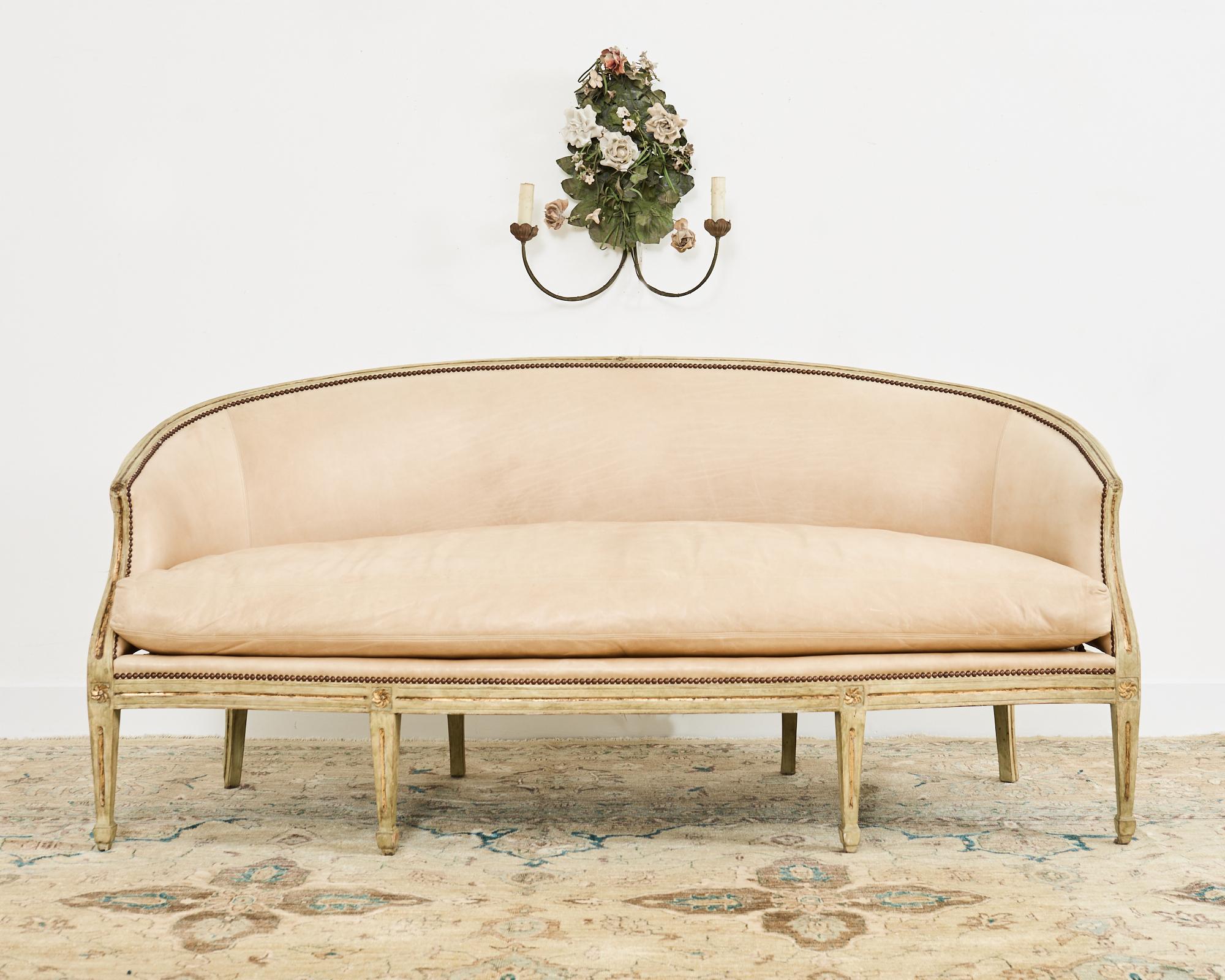 Opulent canape sofa or cabriole sofa made in the neoclassical Gustavian taste. The sofa features a long gracefully curved back. The beech frame is intentionally aged with a weathered patina on the painted finish having parcel gilt accents. The sofa
