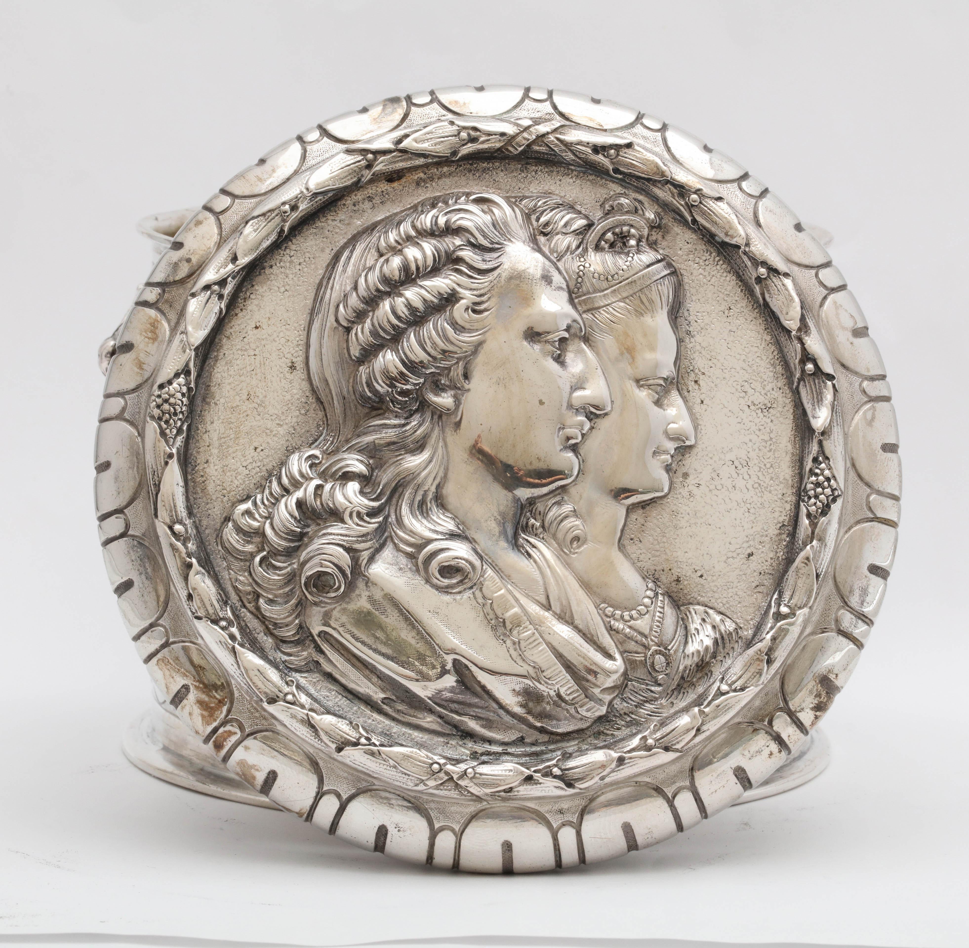 Neoclassical, continental silver (.800) table box, Germany, circa 1895, having Hannau marks.
Chased laurel swags are suspended from ram's heads. Cover is embossed with what looks to be a royal couple. Interior is gilded. Measures 4 1/2 inches high