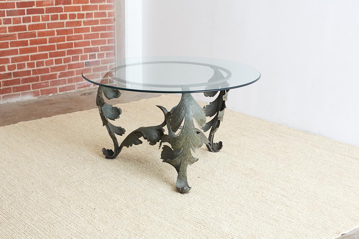 Dramatic hand-forged iron dining table or garden table featuring a scrolled acanthus leaf design made in the neoclassical taste. The base has a round iron ring top that can accept any size glass and is supported by three strong legs conjoined in the