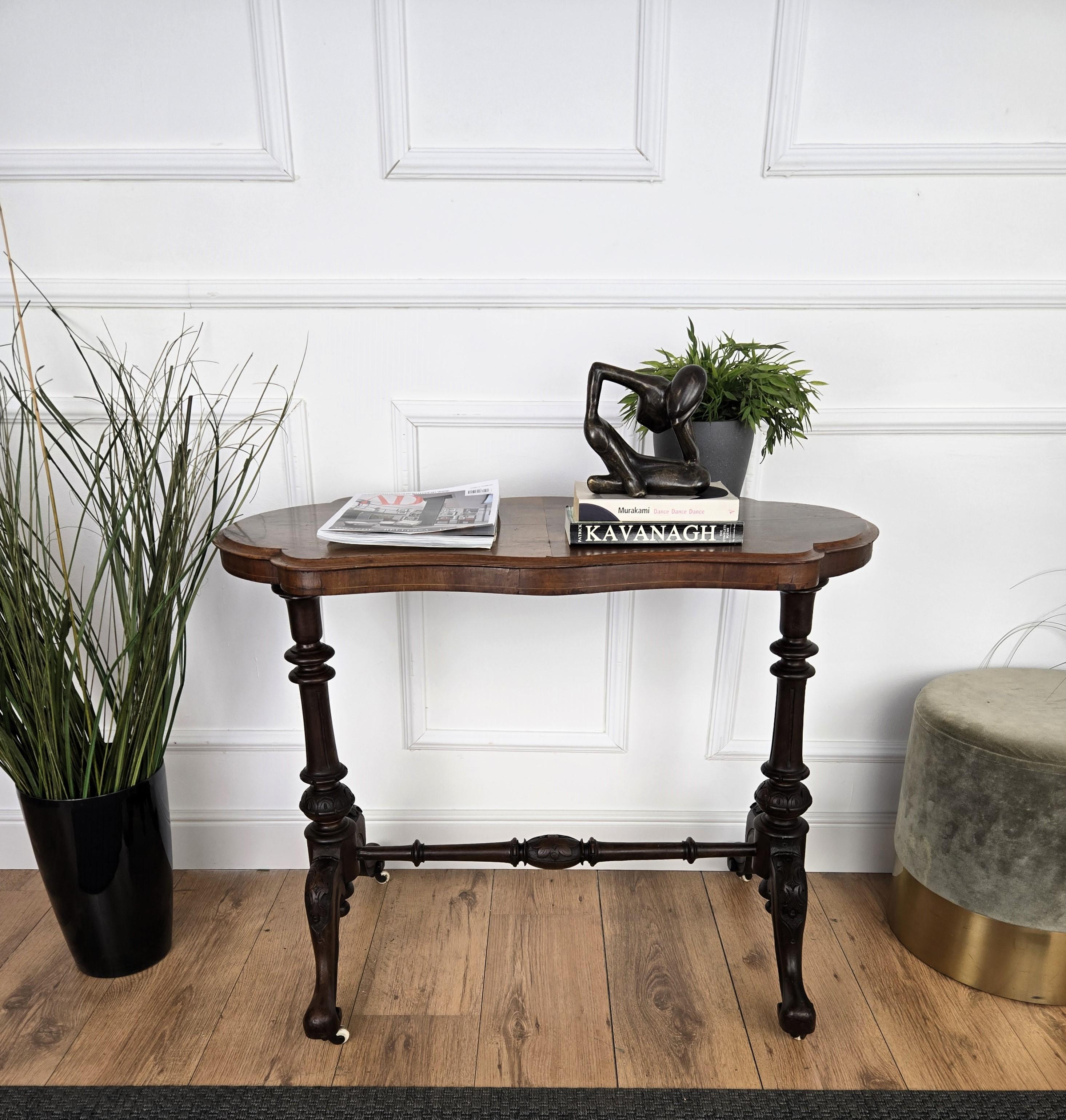 A beautiful Italian walnut side table with great details and frames, oval shaped with beautiful wood burl top and carved legs with central stretcher completed by the ceramic wheels finials. A very elegant, modern and classic piece that showcases the